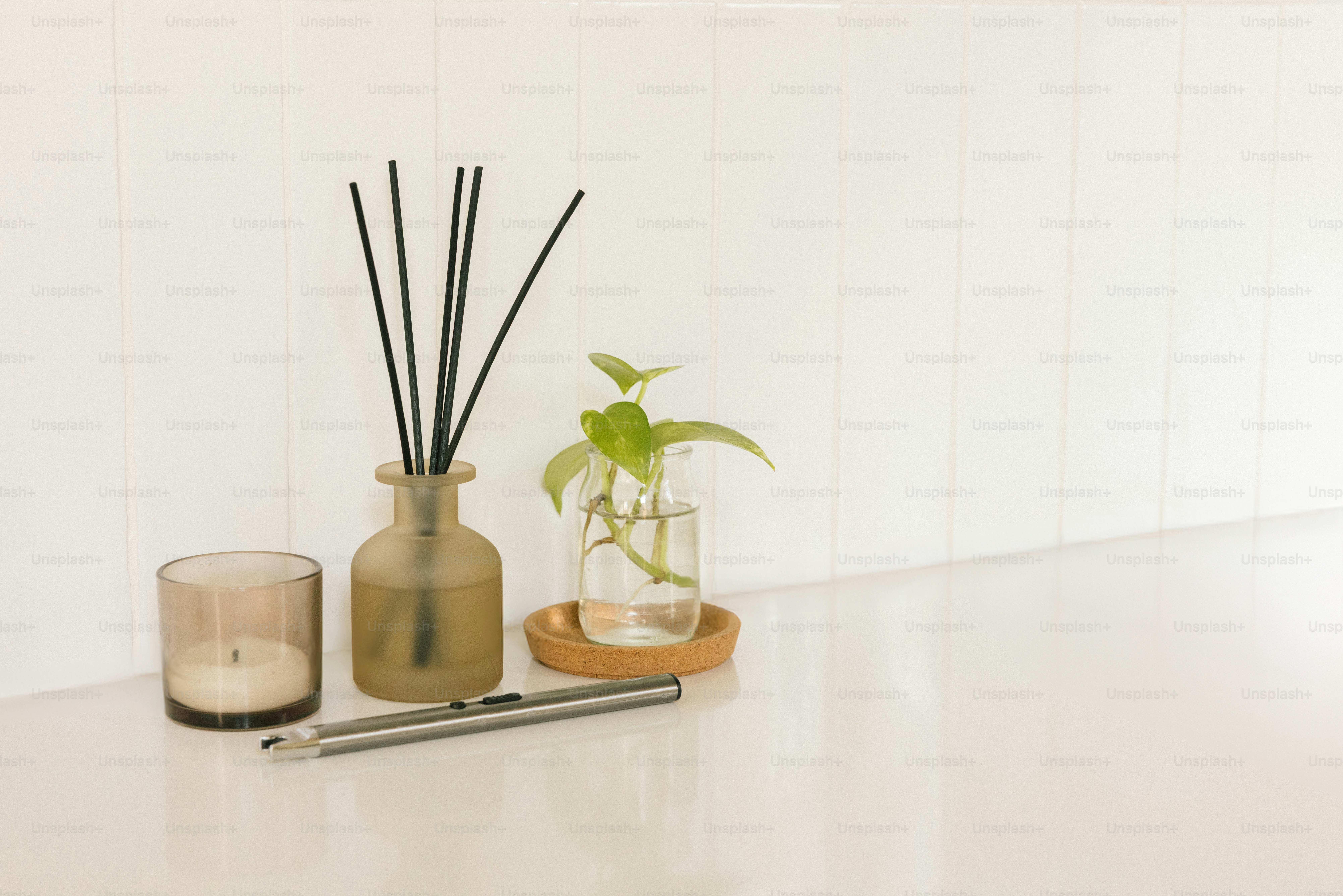 디퓨저, 양초, 그리고 흰 표면 위에 식물을 꽂는 것.