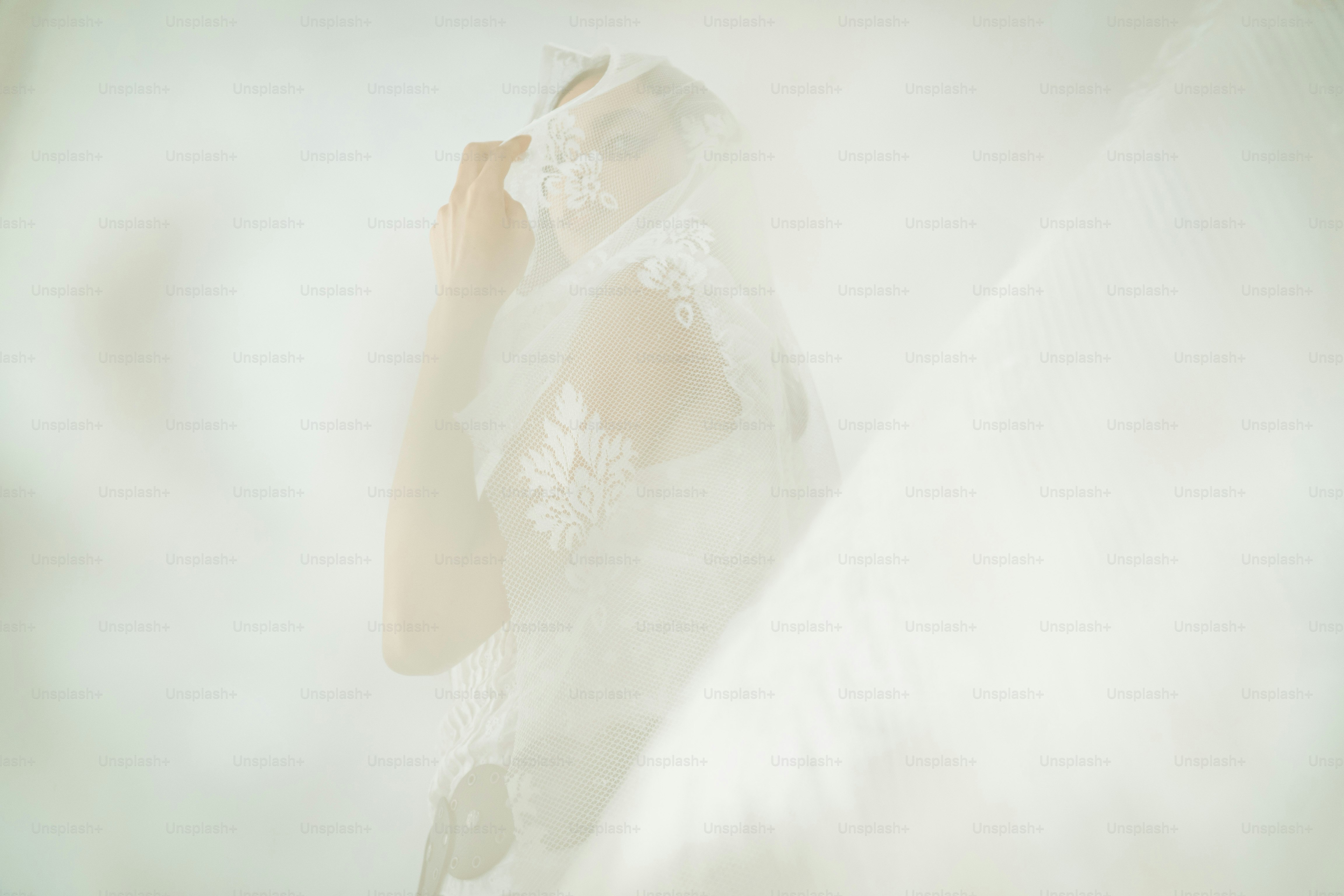 A bride in a white veil touches her face.