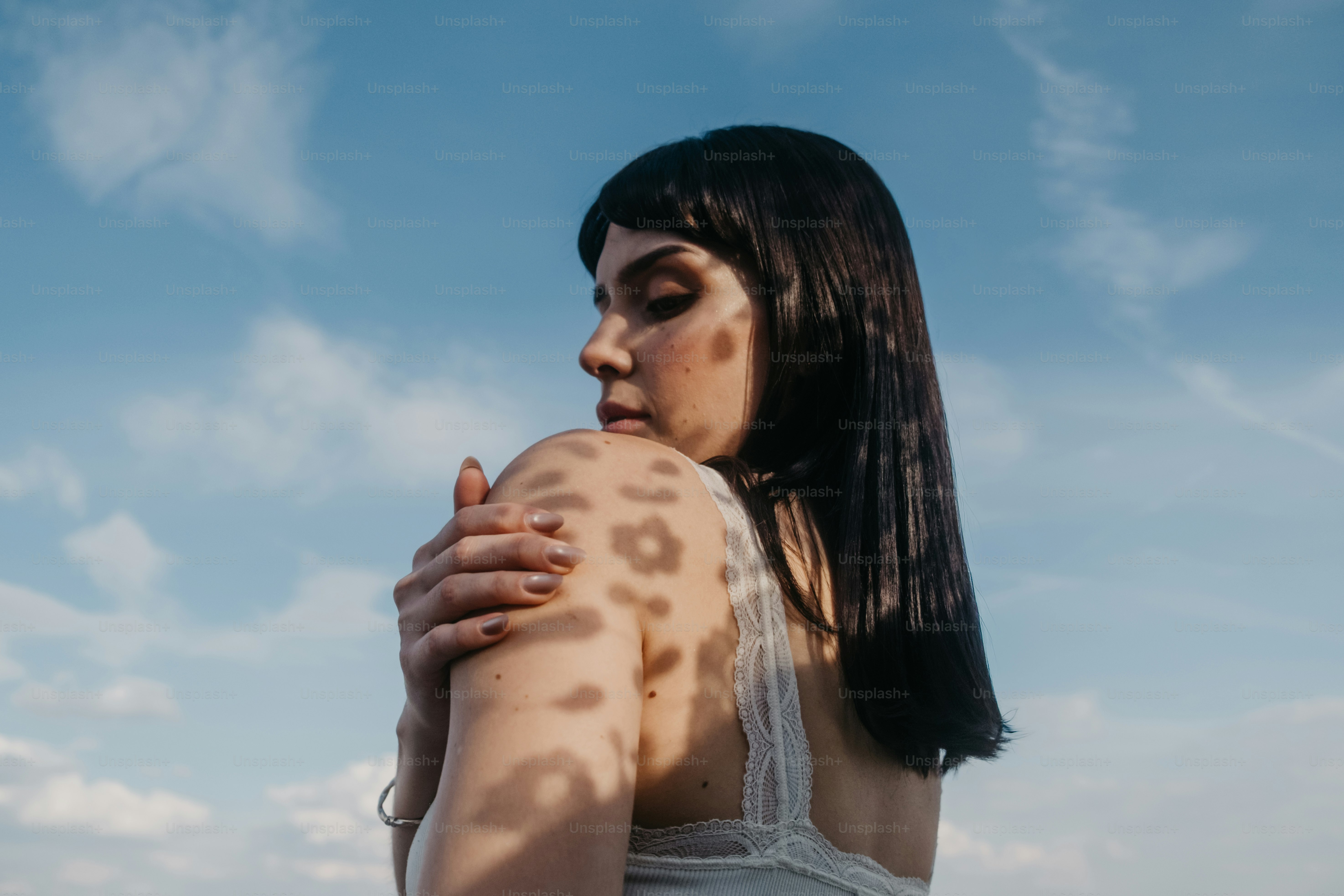 Donna con ombre decorate sul braccio contro il cielo