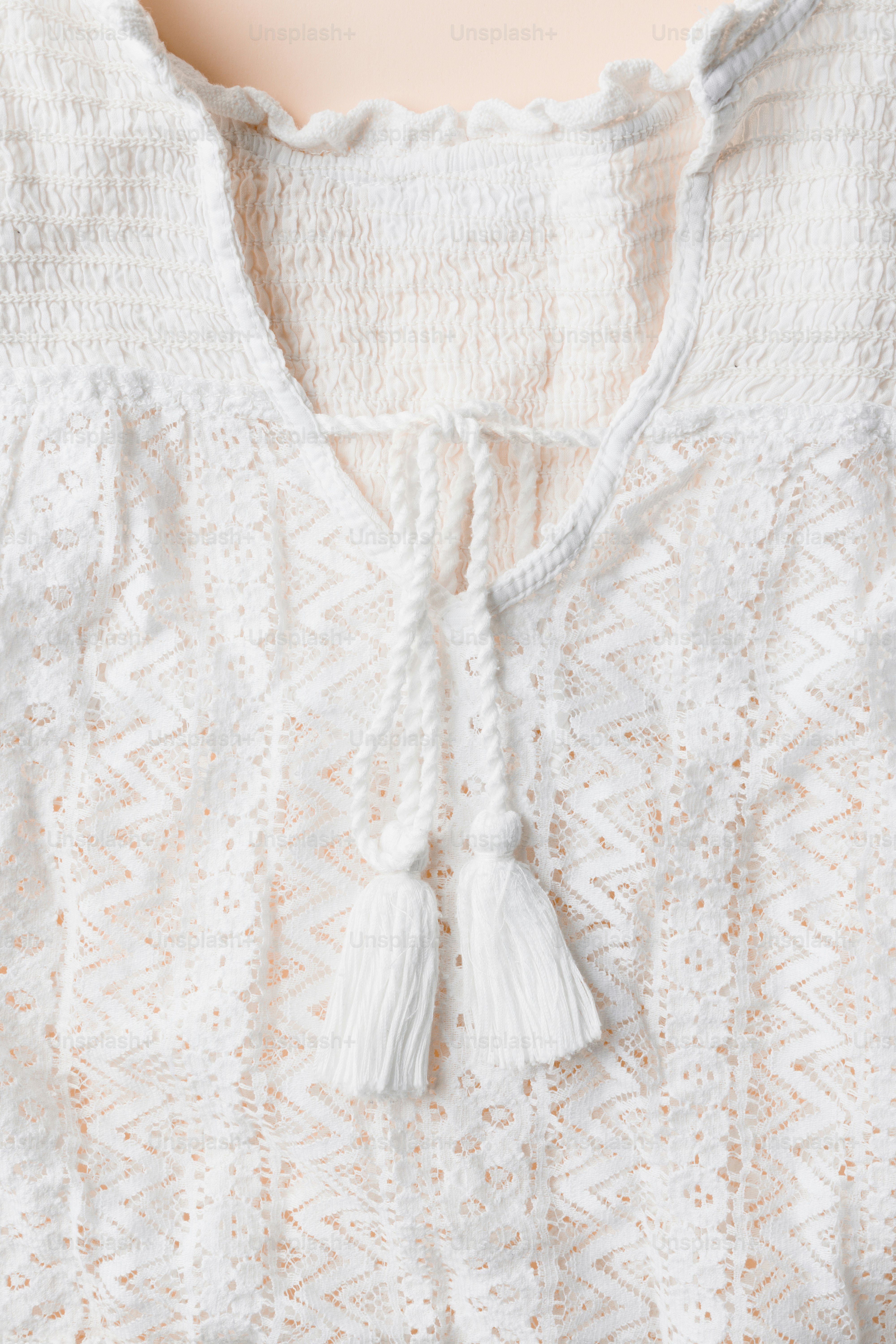 Close-up of a white lacy blouse with tassels