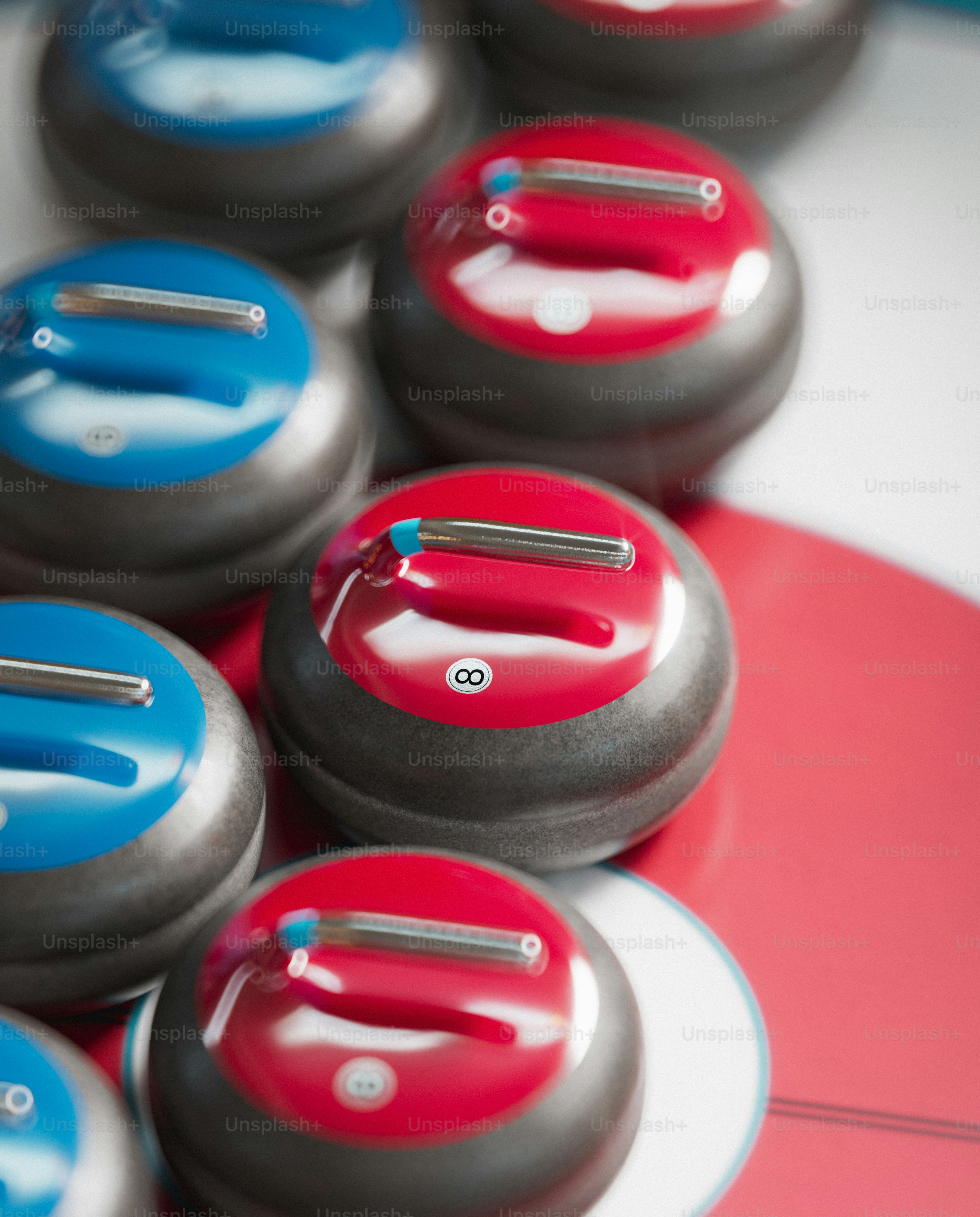 Red and blue curling stones on ice.