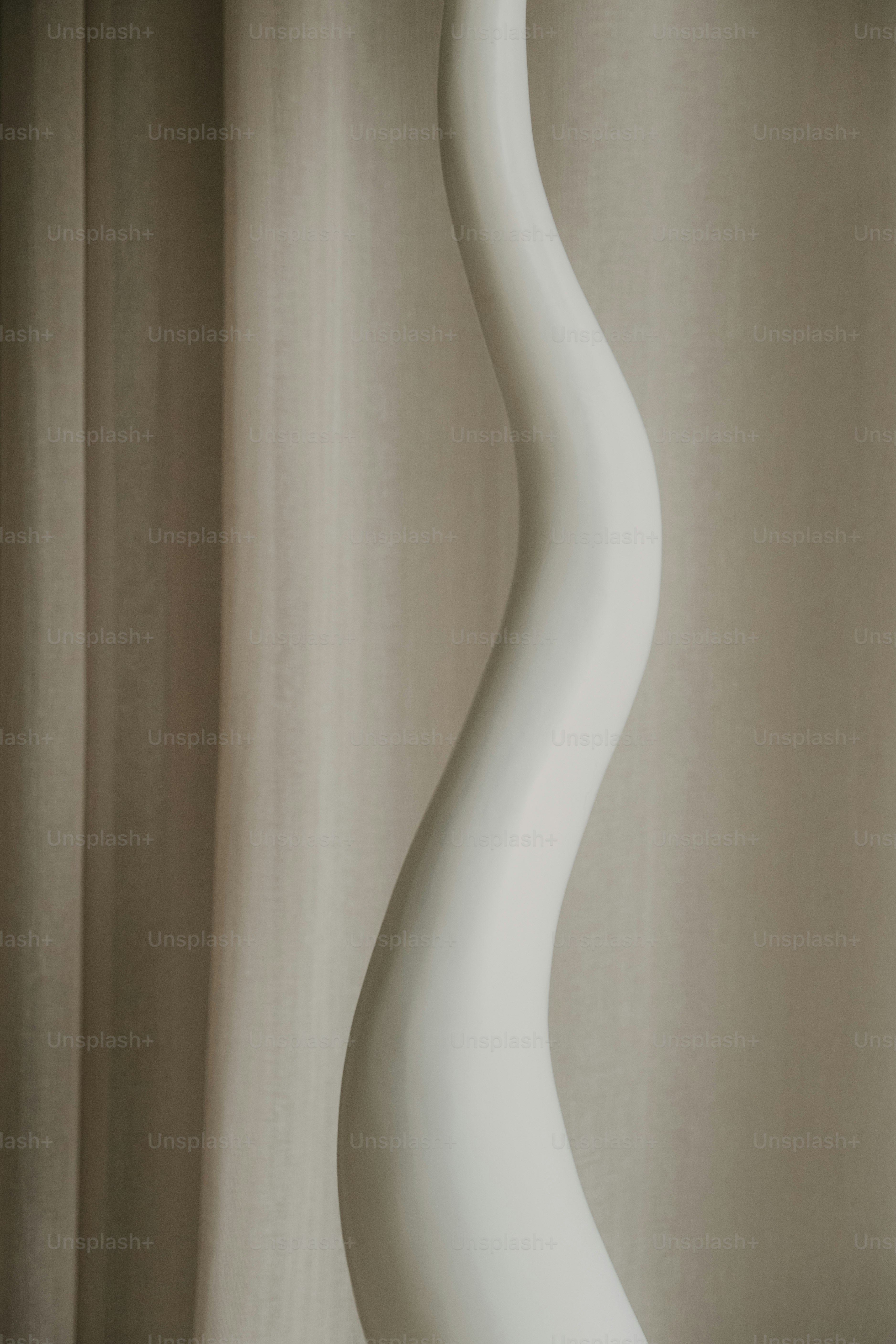 A tall, white, abstract sculpture against a neutral background.