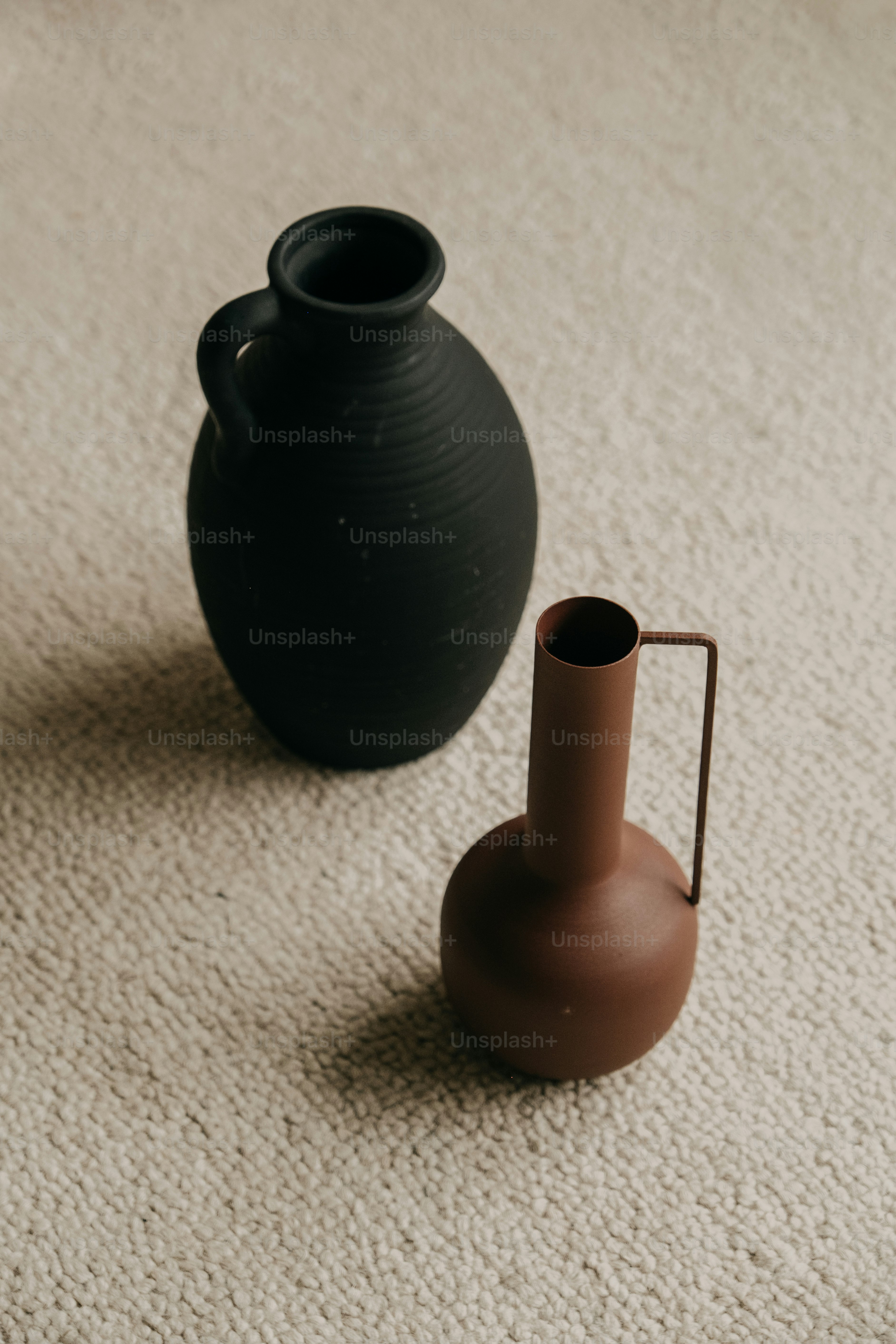 Two decorative vases on a textured surface