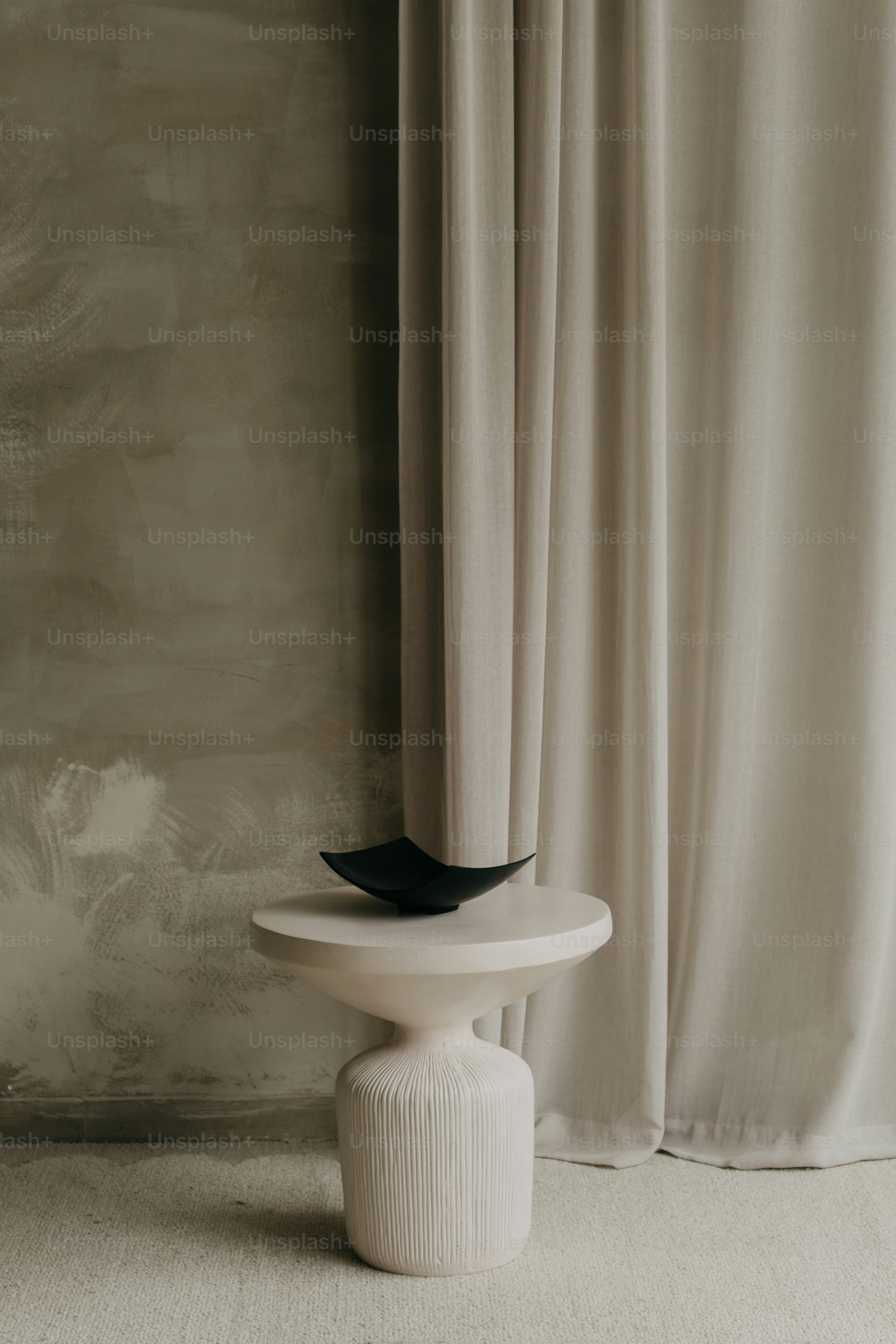 A dark bowl rests on a light-colored pedestal table.