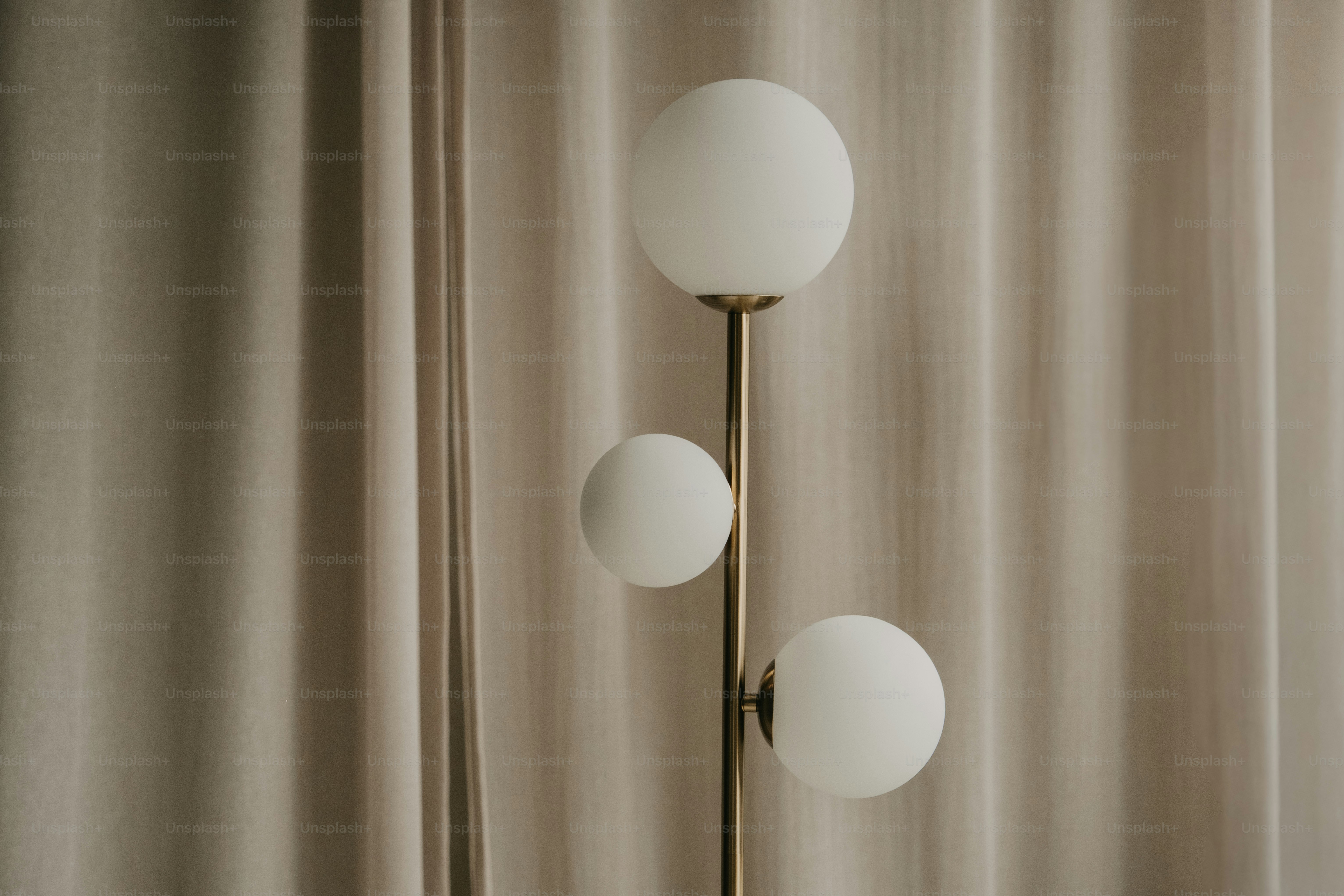 A modern floor lamp with three white globes.