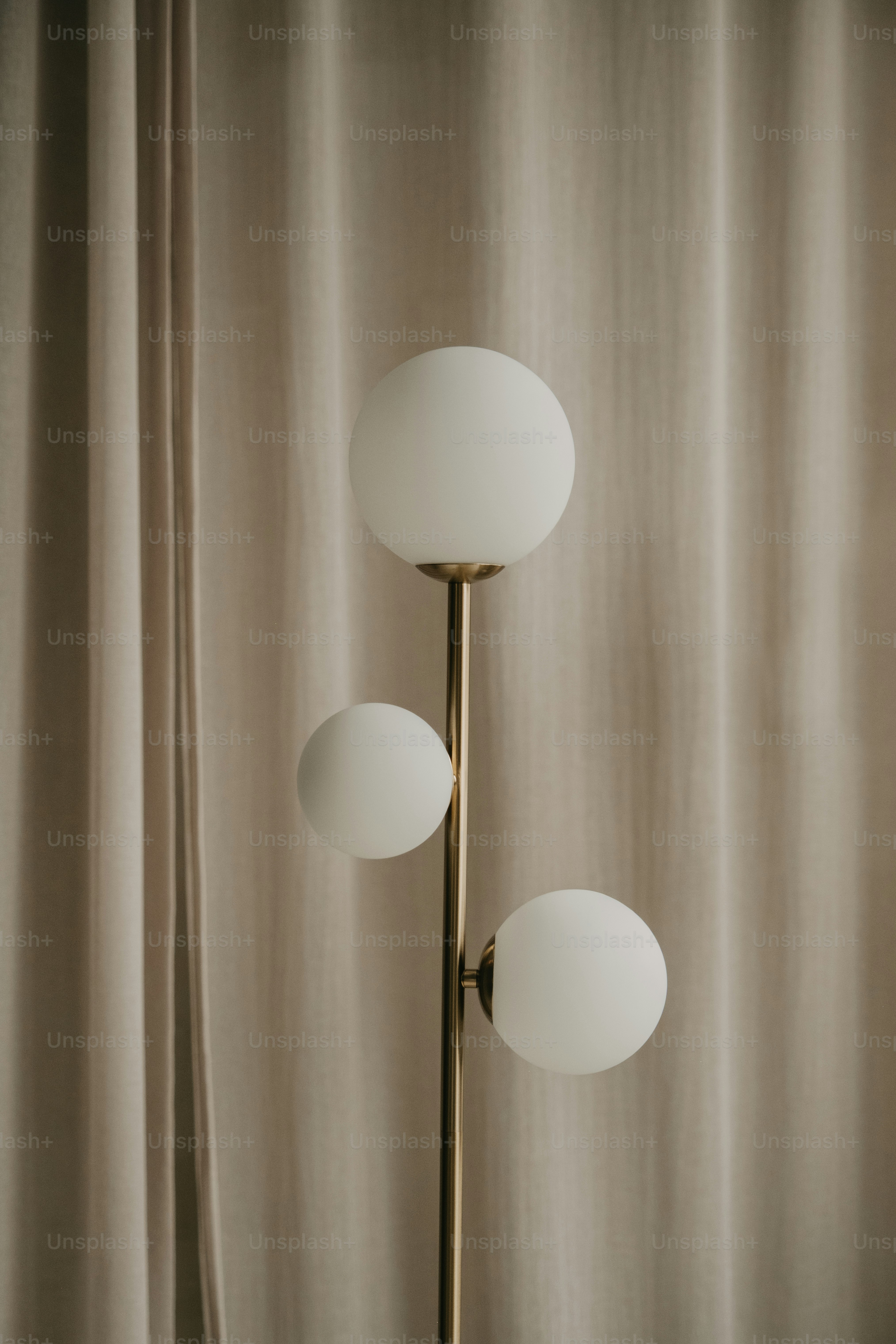 A modern floor lamp with three white globes.