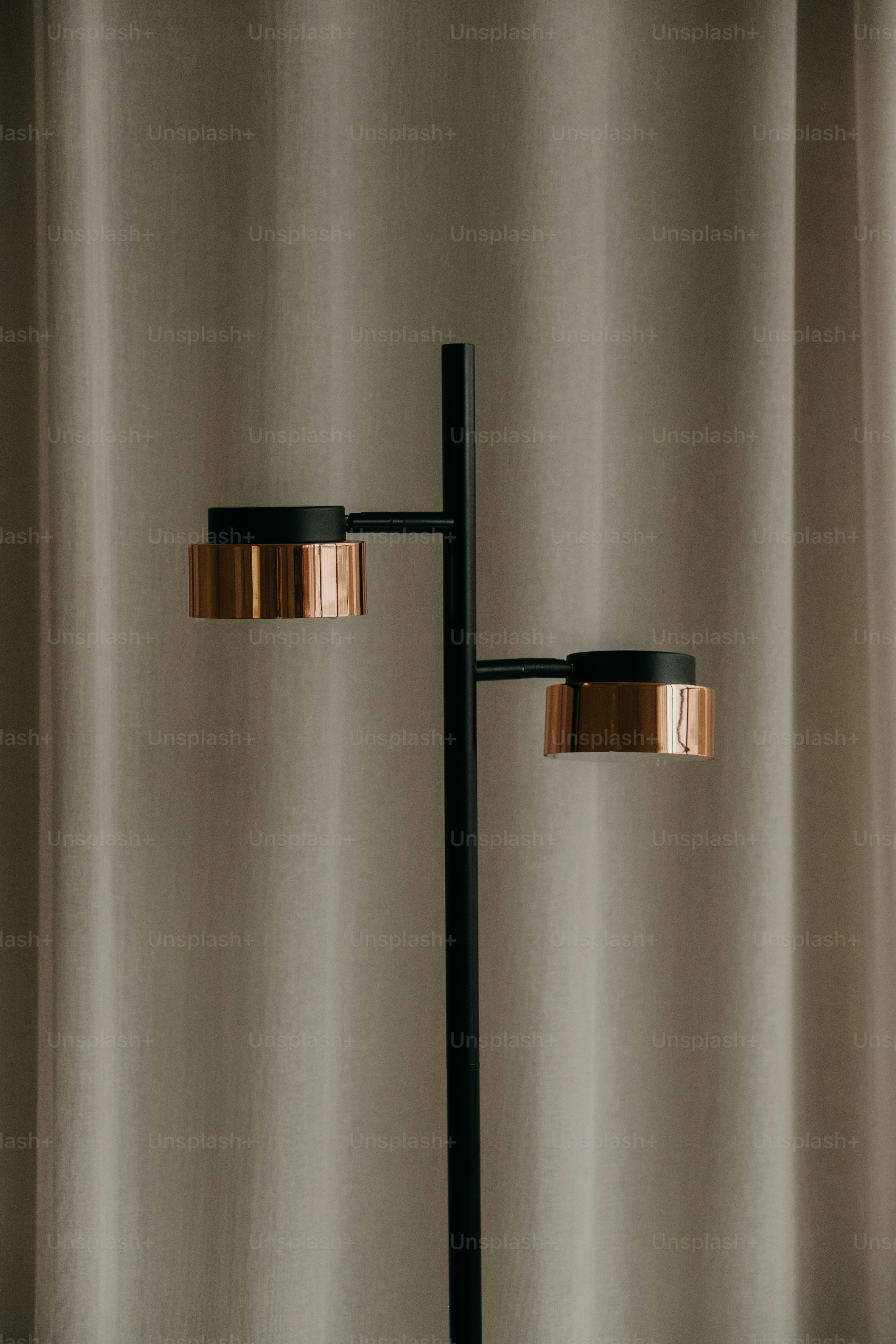 A modern black floor lamp with copper accents.