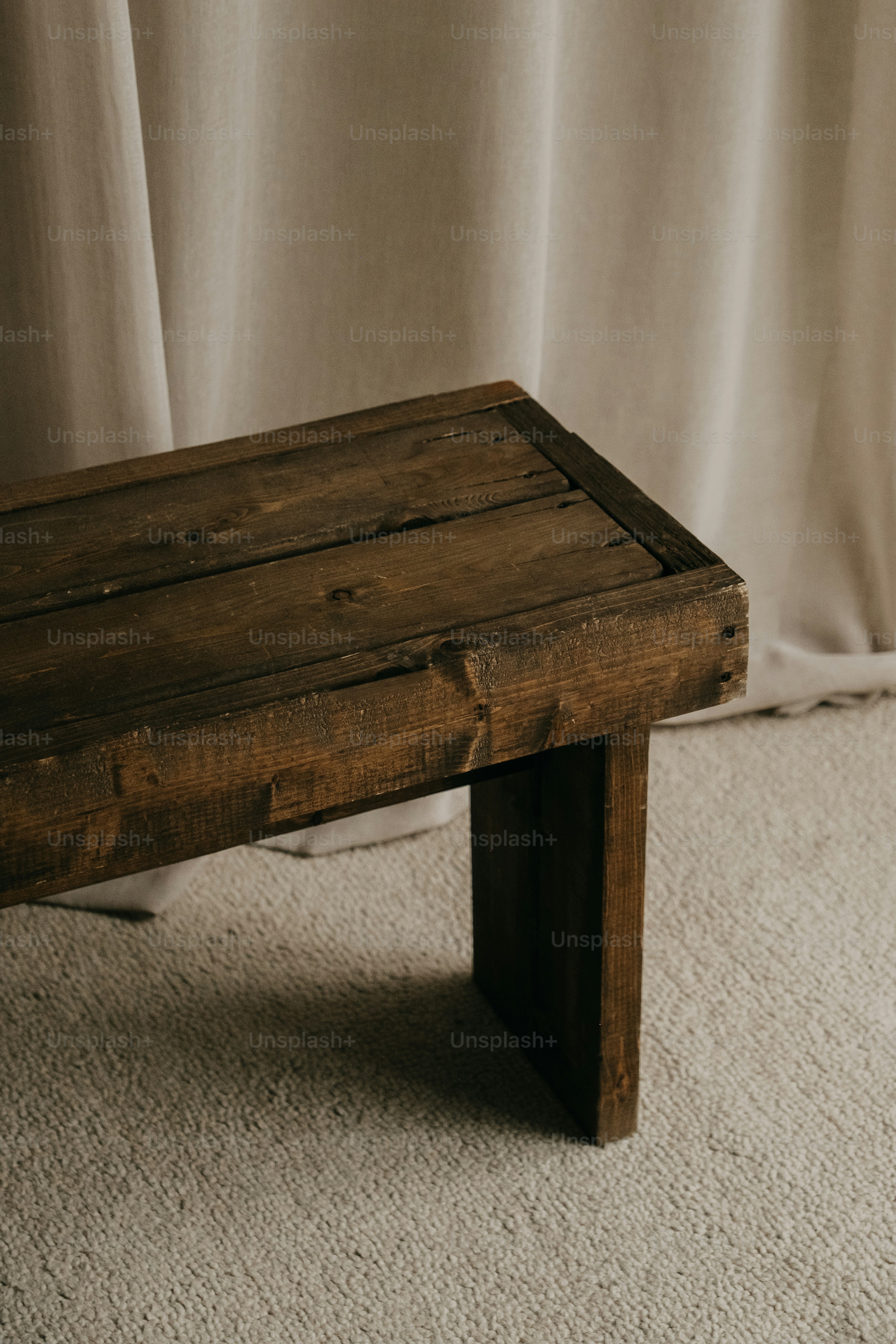 A rustic wooden bench against a draped curtain