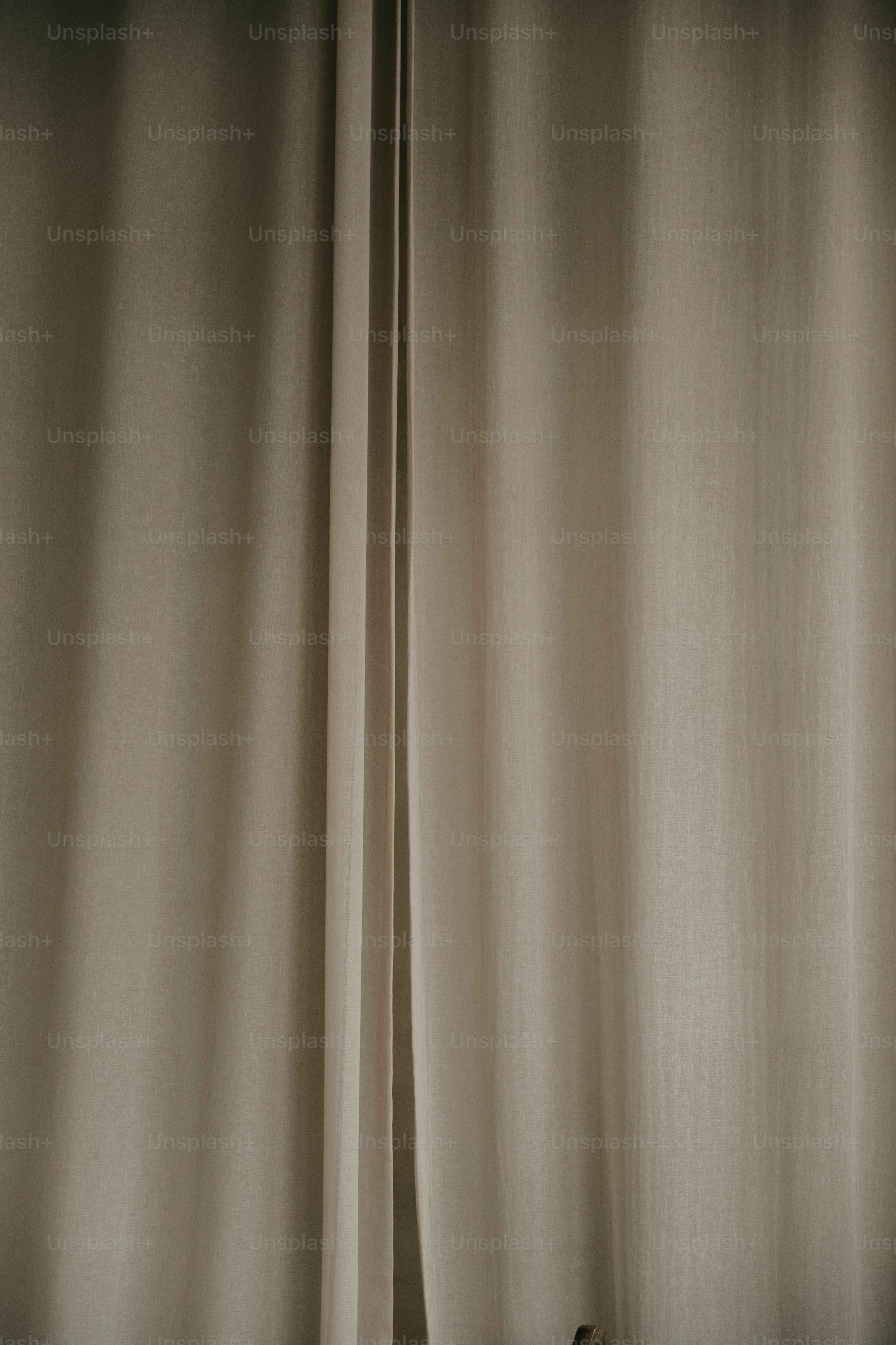 A closed beige curtain with vertical folds