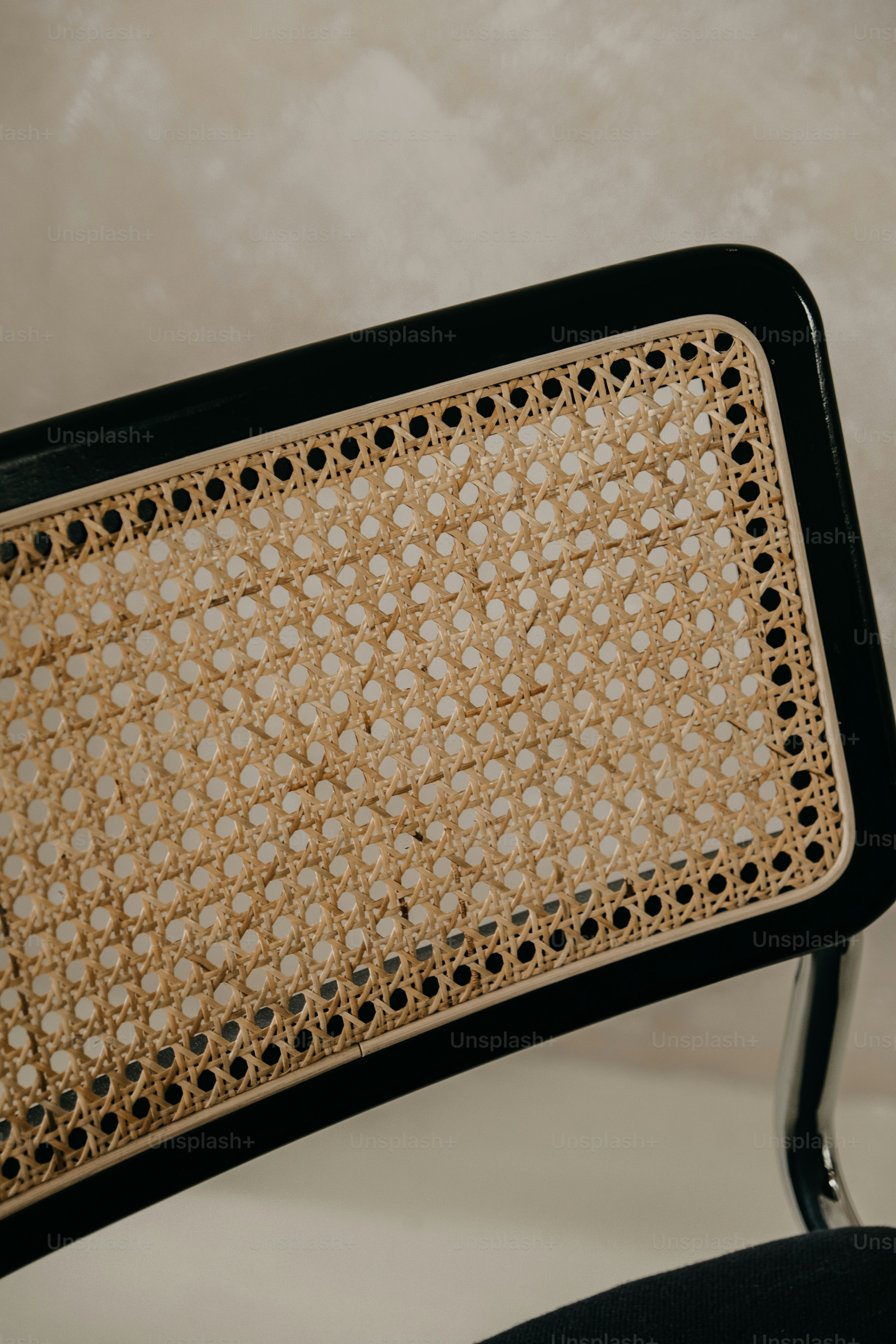 Close-up of a cane-backed chair with black frame.