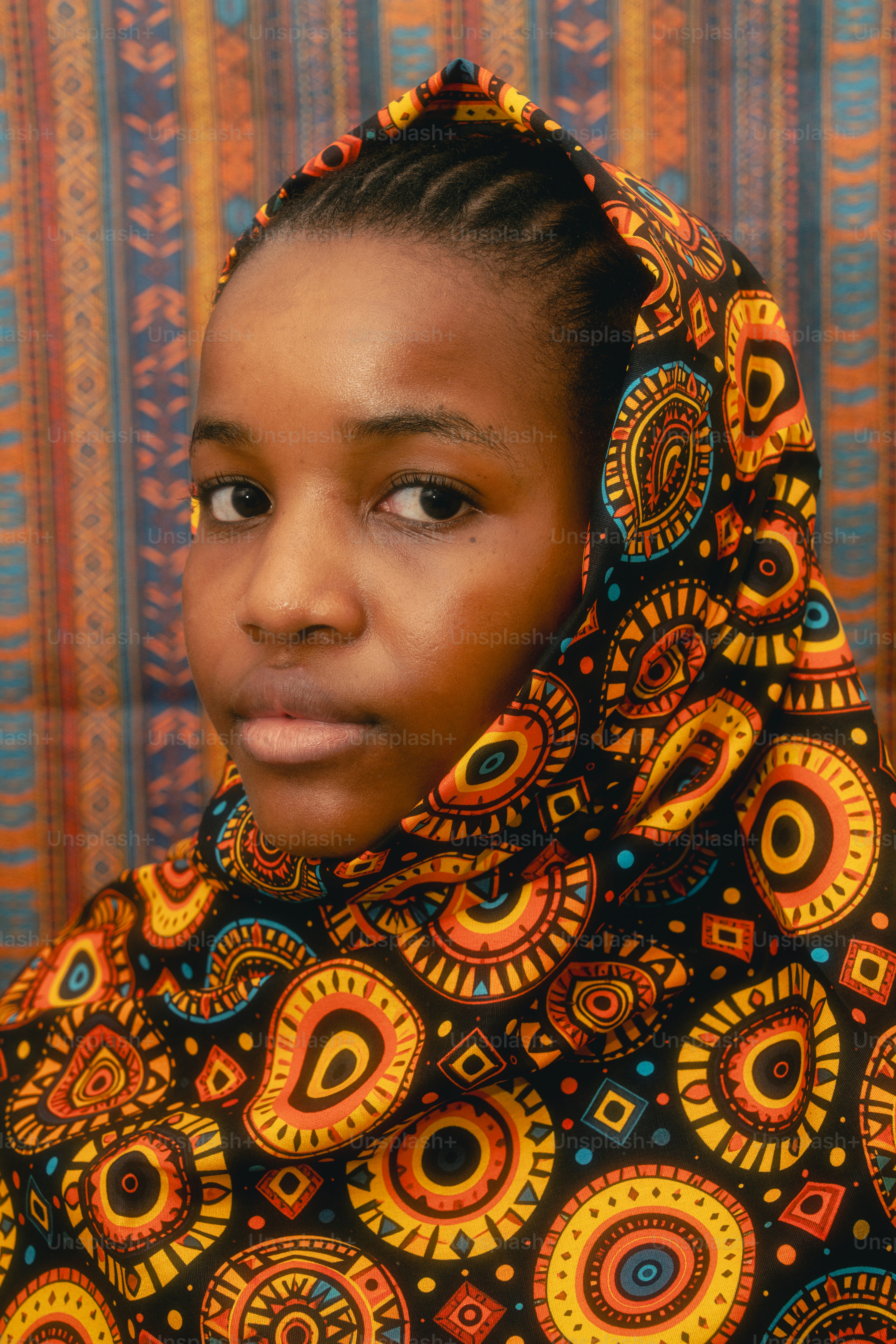 A young girl wearing a colorful patterned headscarf.