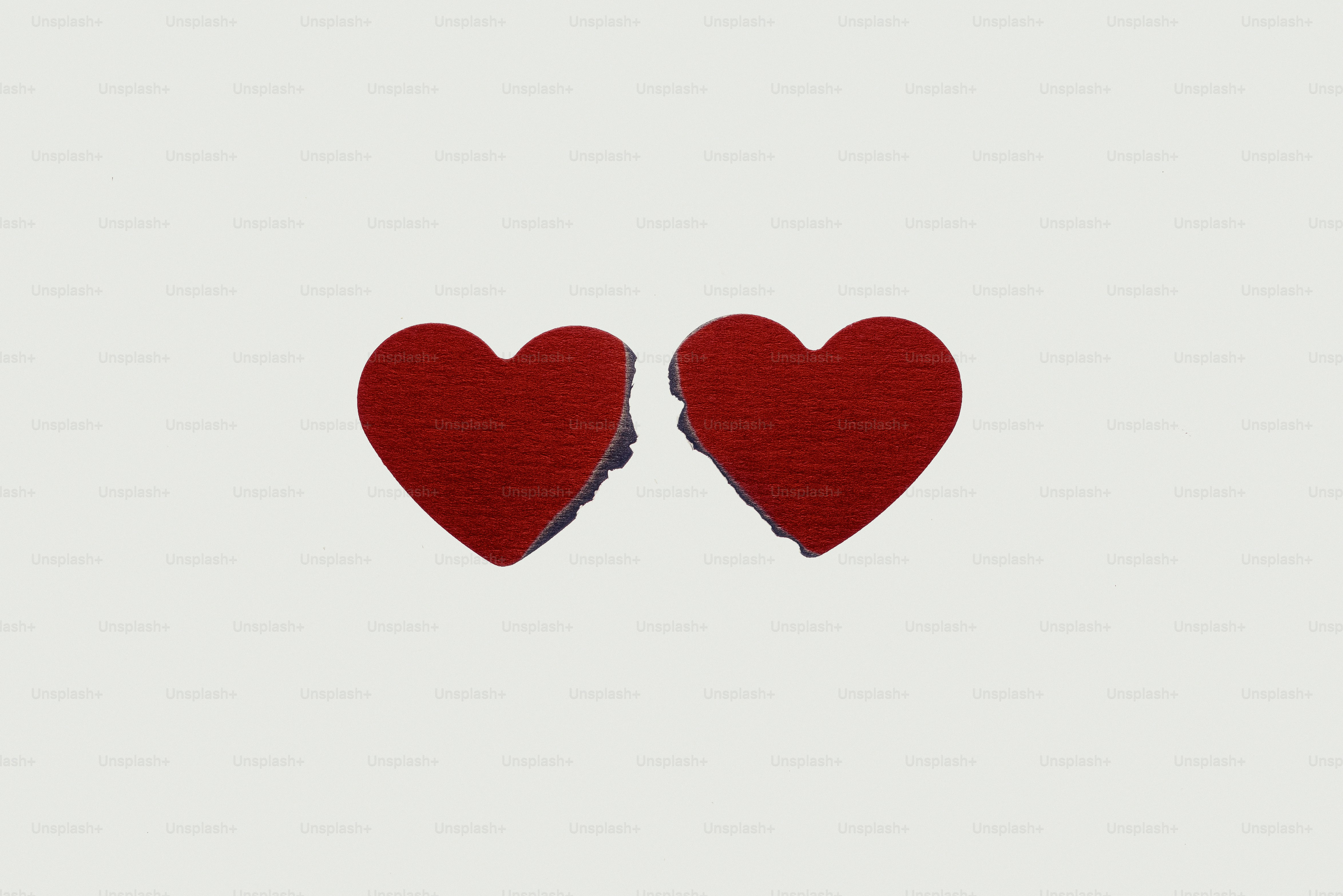 Two red hearts, one broken, on white background