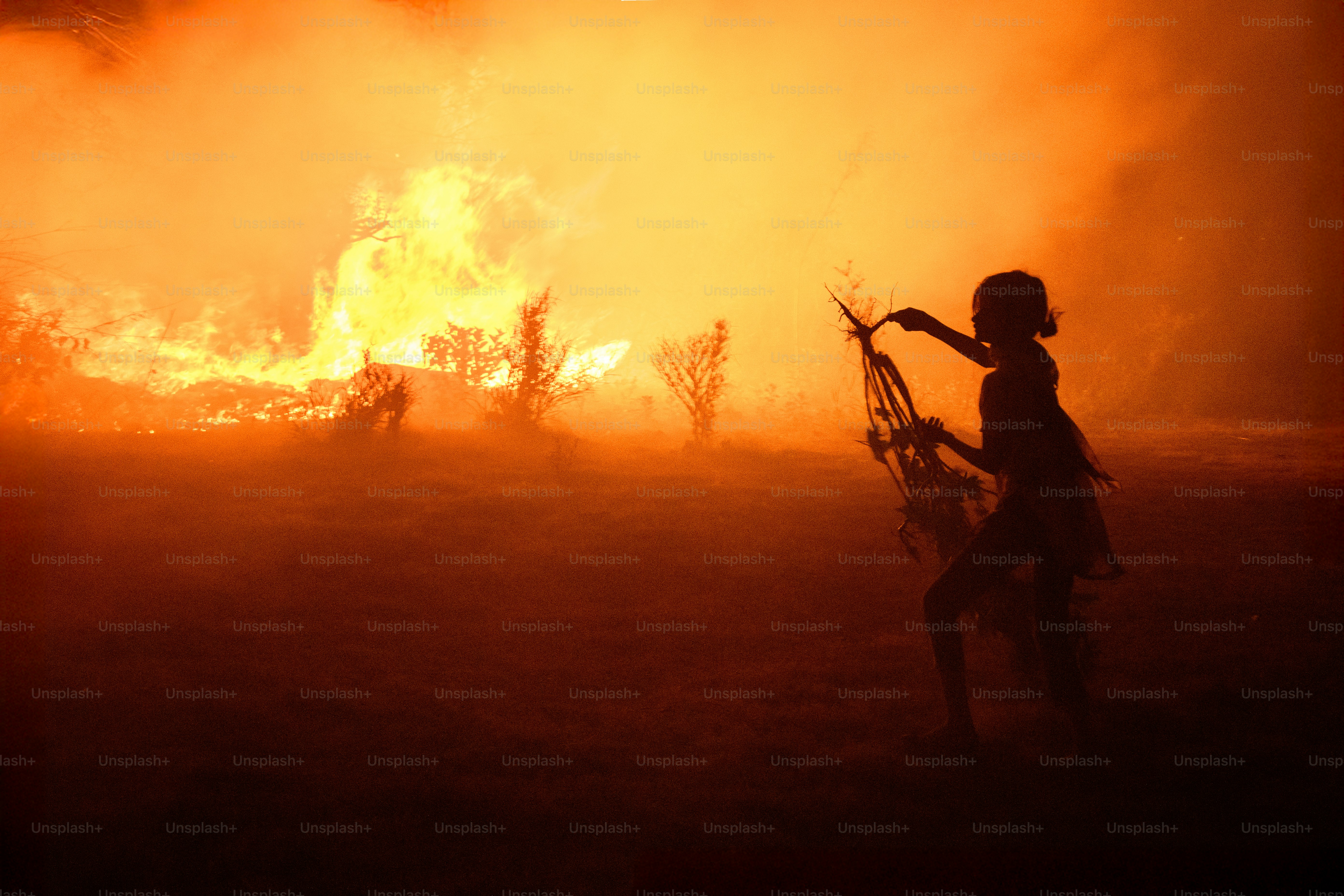 Silhouette of person against a large wildfire.