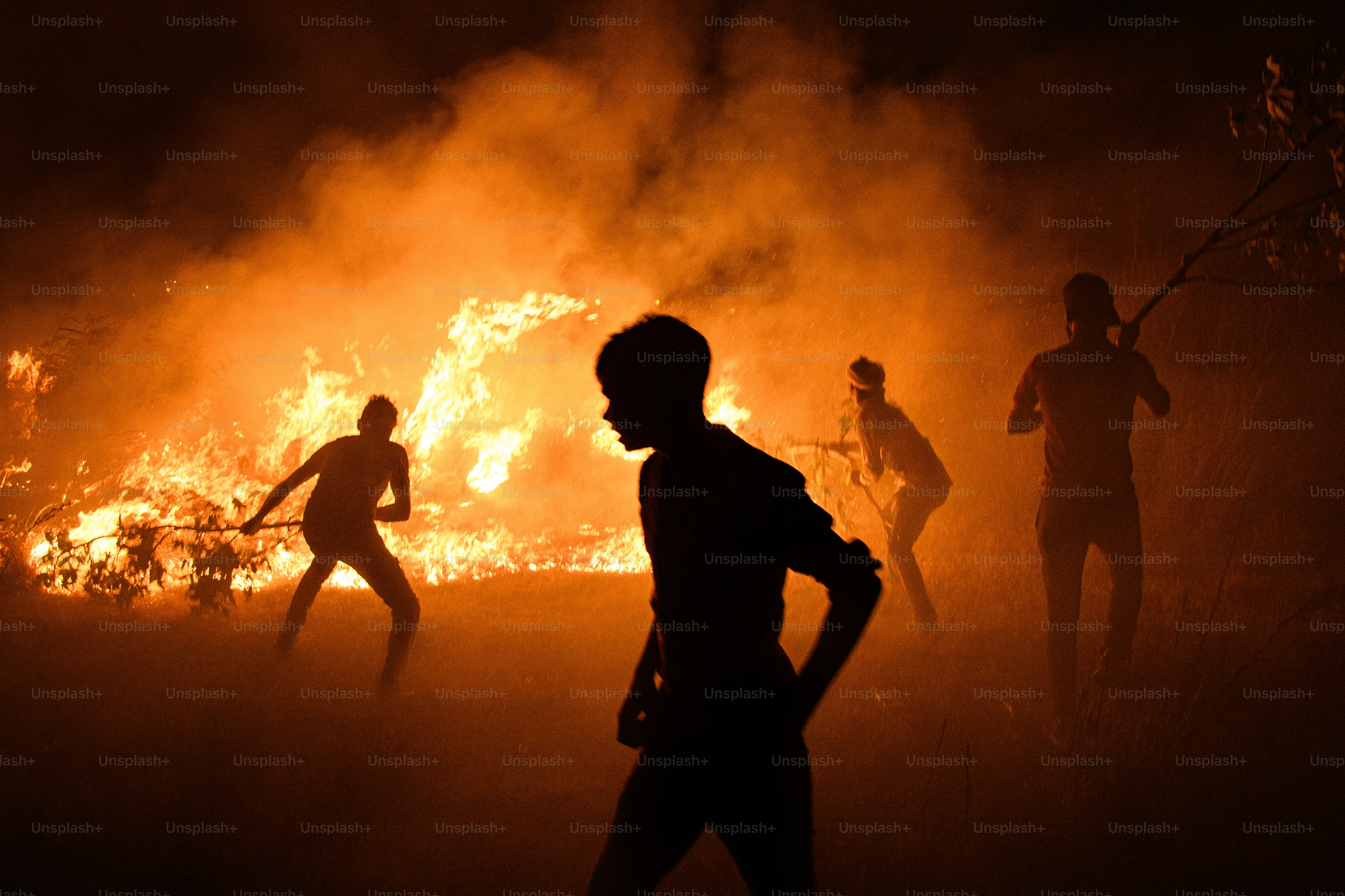 Silhouettes of people against a large bonfire at night
