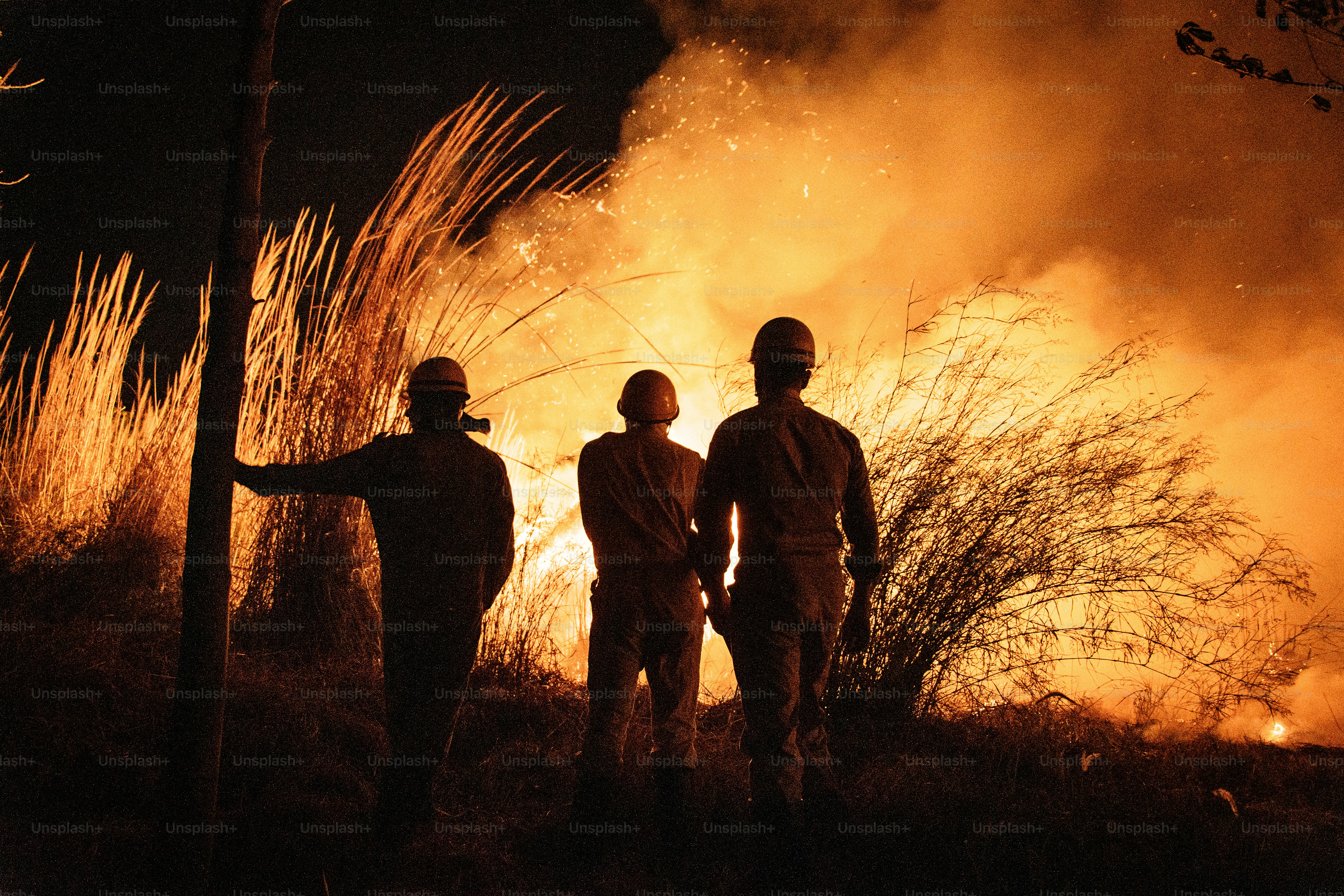 People watch a large bonfire at night