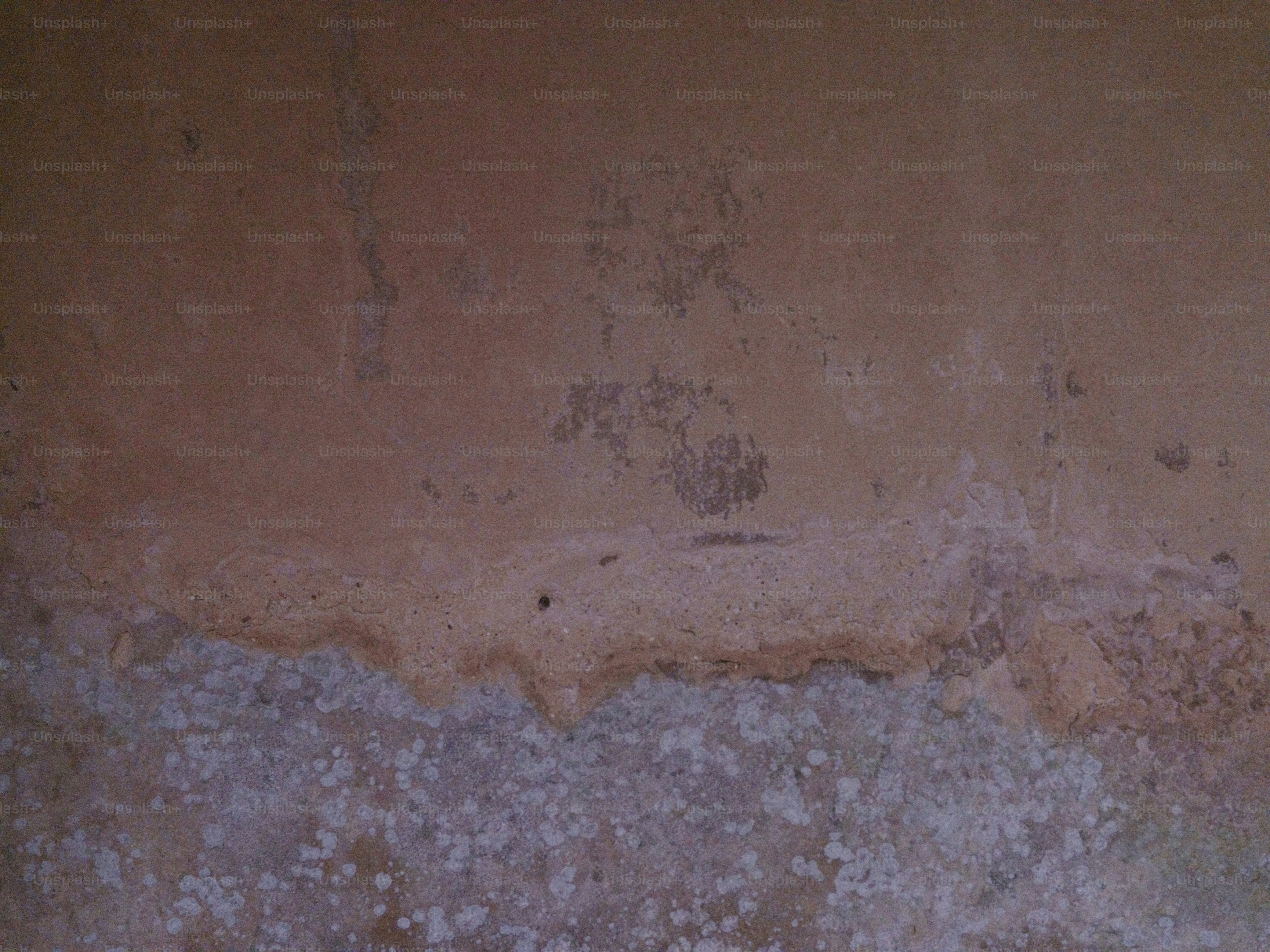 A textured wall with water damage and mold