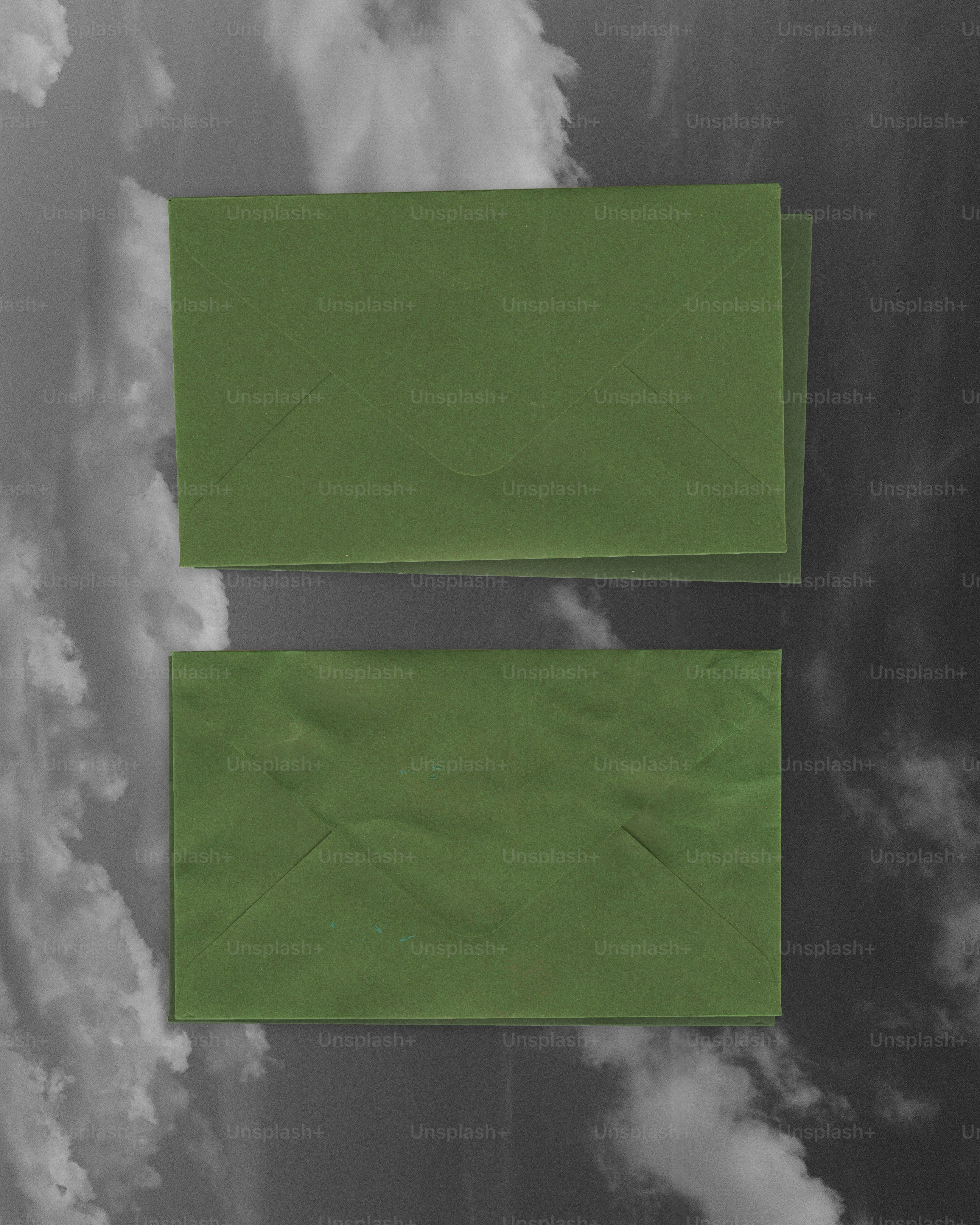 Deux enveloppes vertes empilées sur un fond nuageux