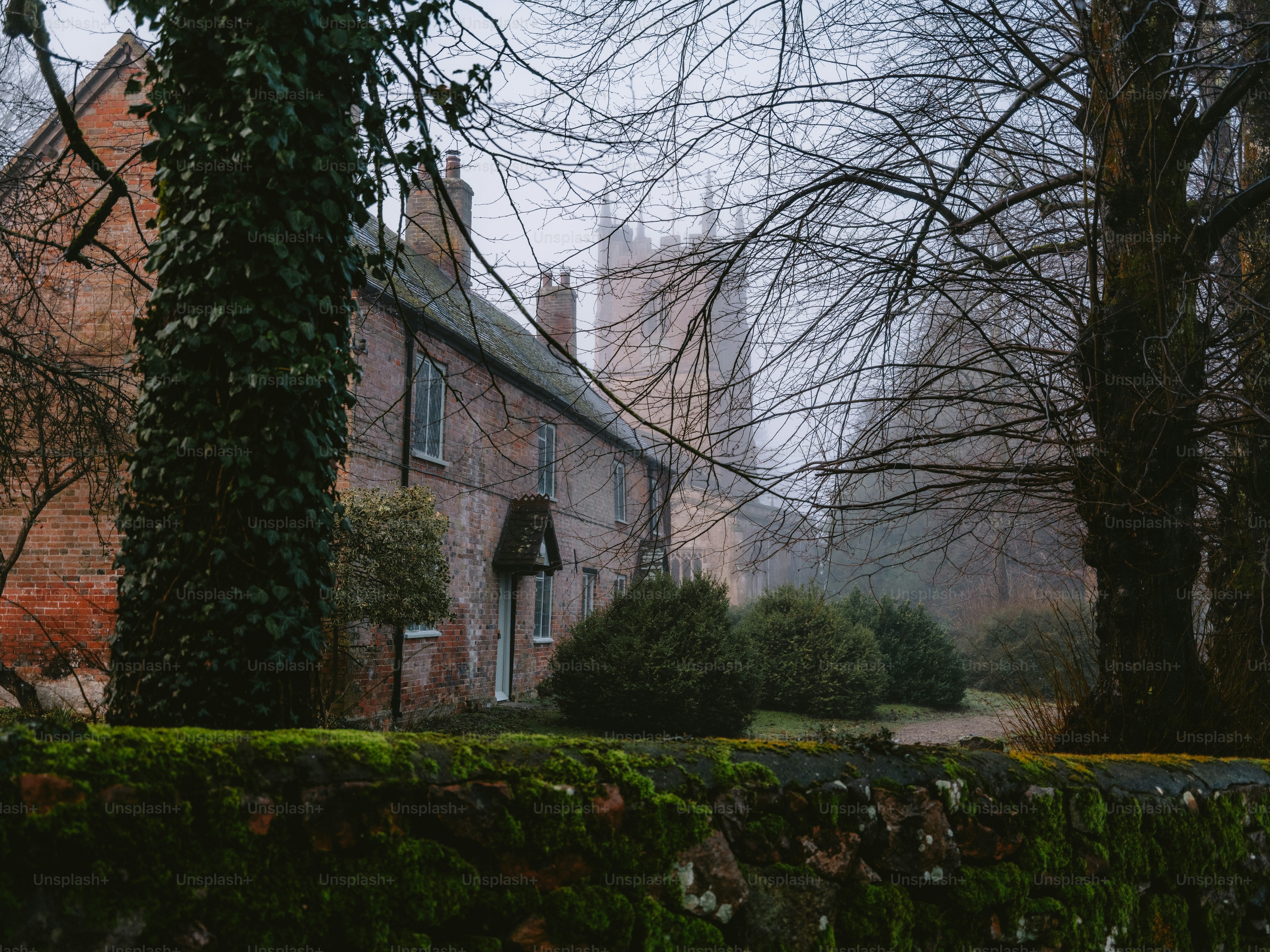 Old brick house with a church spire in the background.