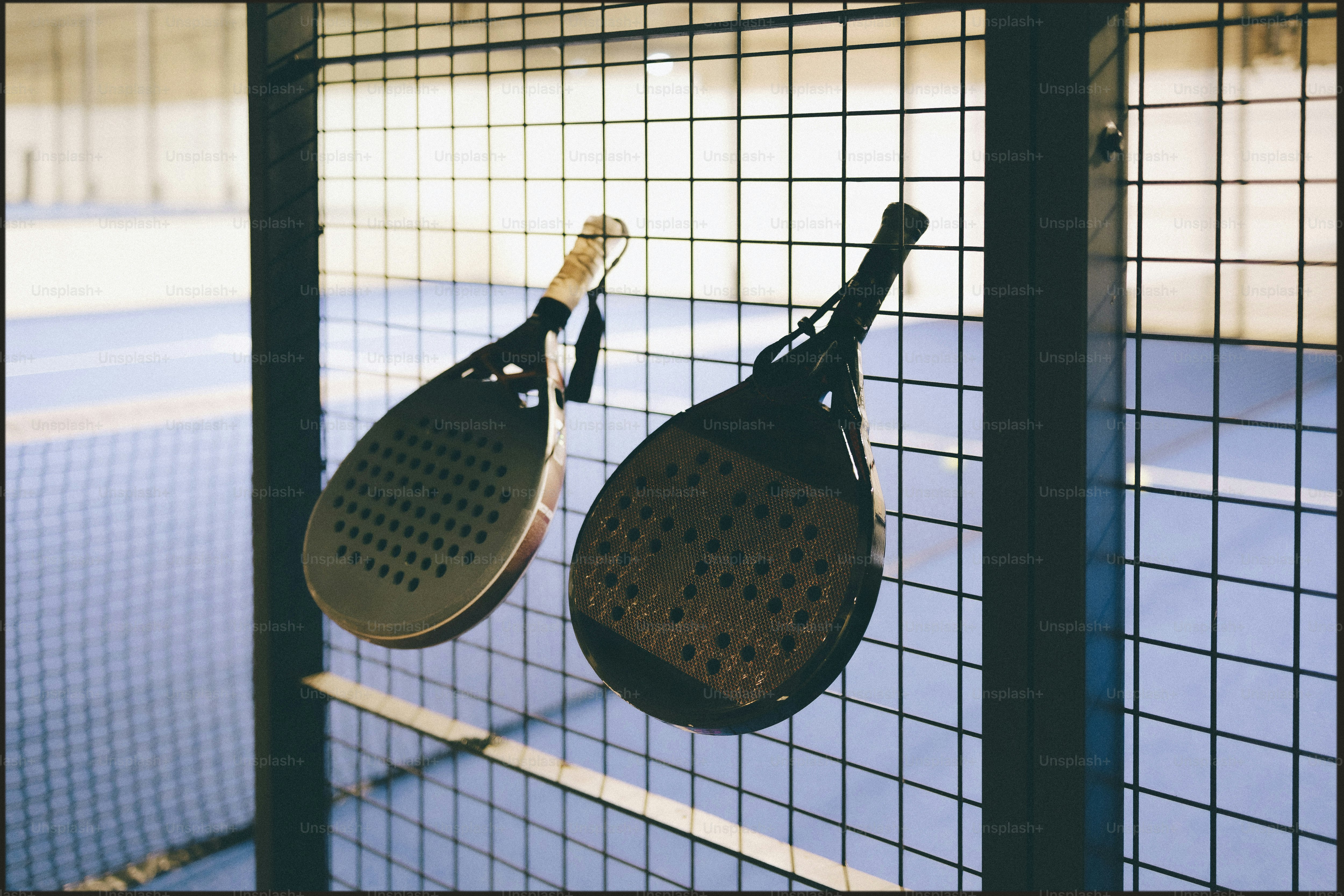 Two padel rackets hanging on a fence photo – Padel Image on Unsplash