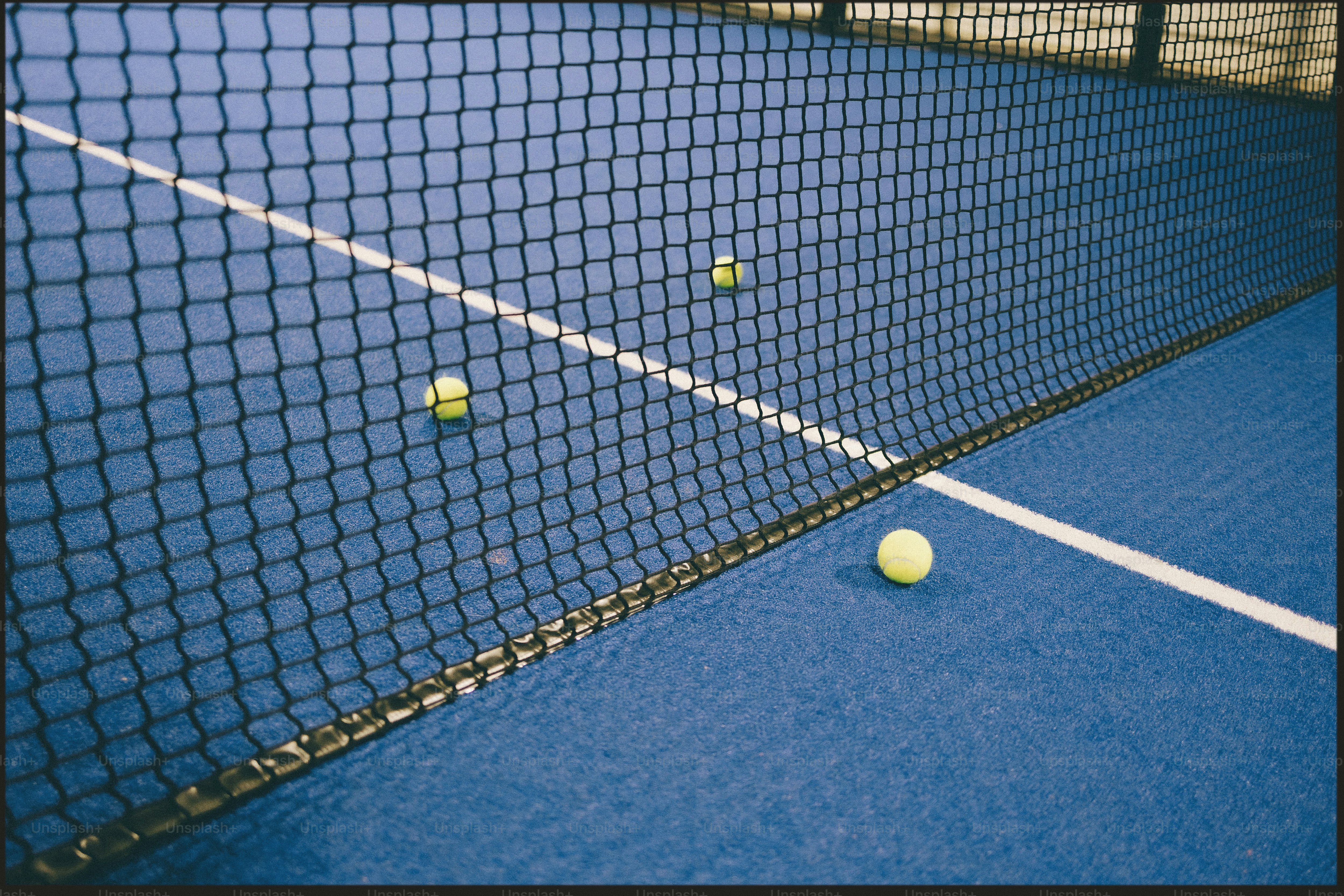 Drei Tennisbälle auf einem blauen Platz in der Nähe des Netzes
