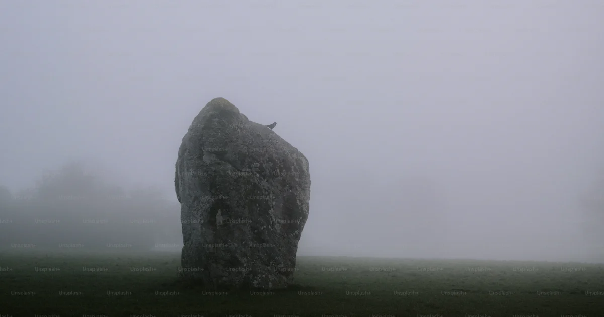 A single standing stone in a foggy field. photo – Dark Image on Unsplash