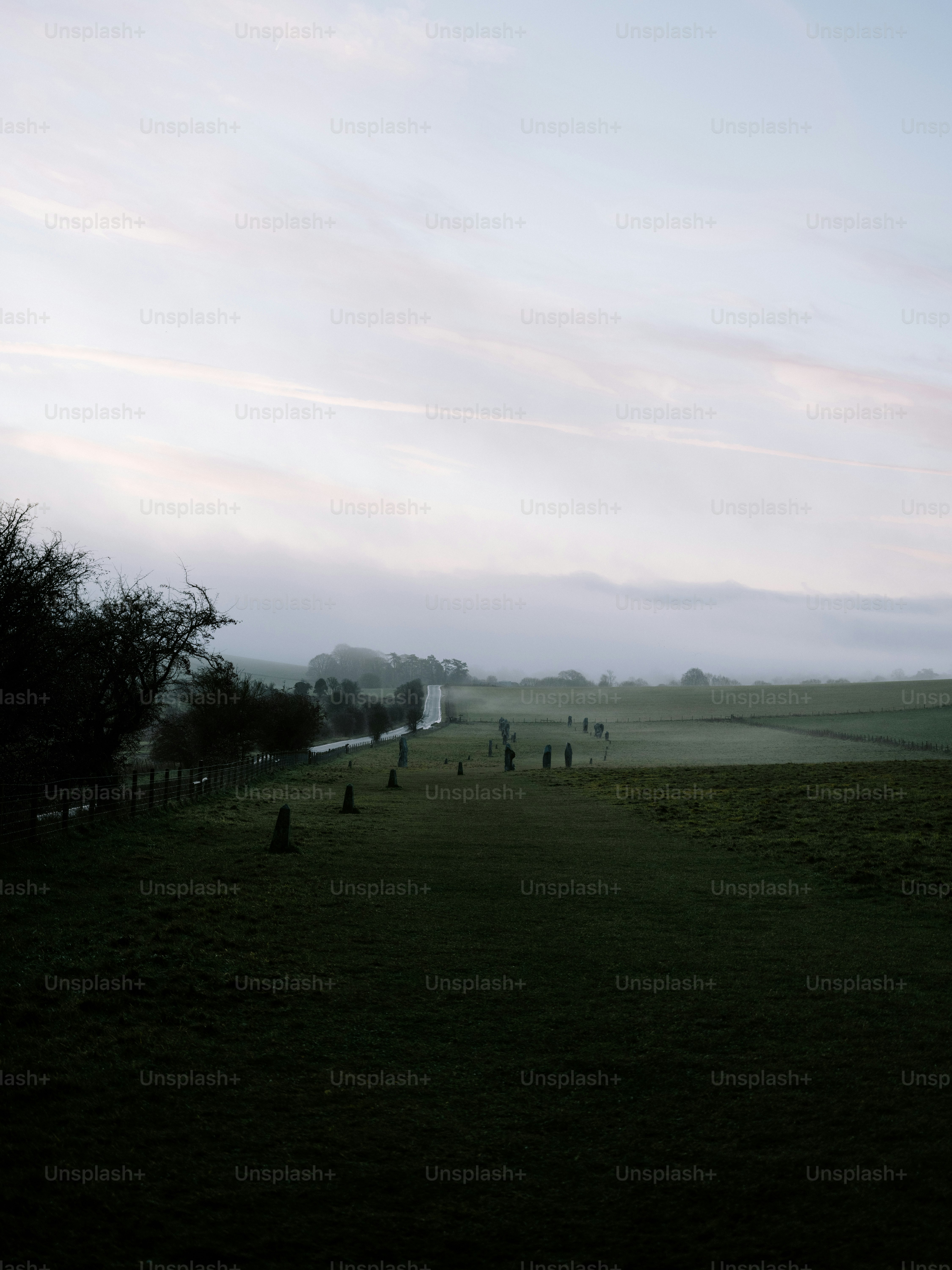 Misty morning over a green field with standing stones.