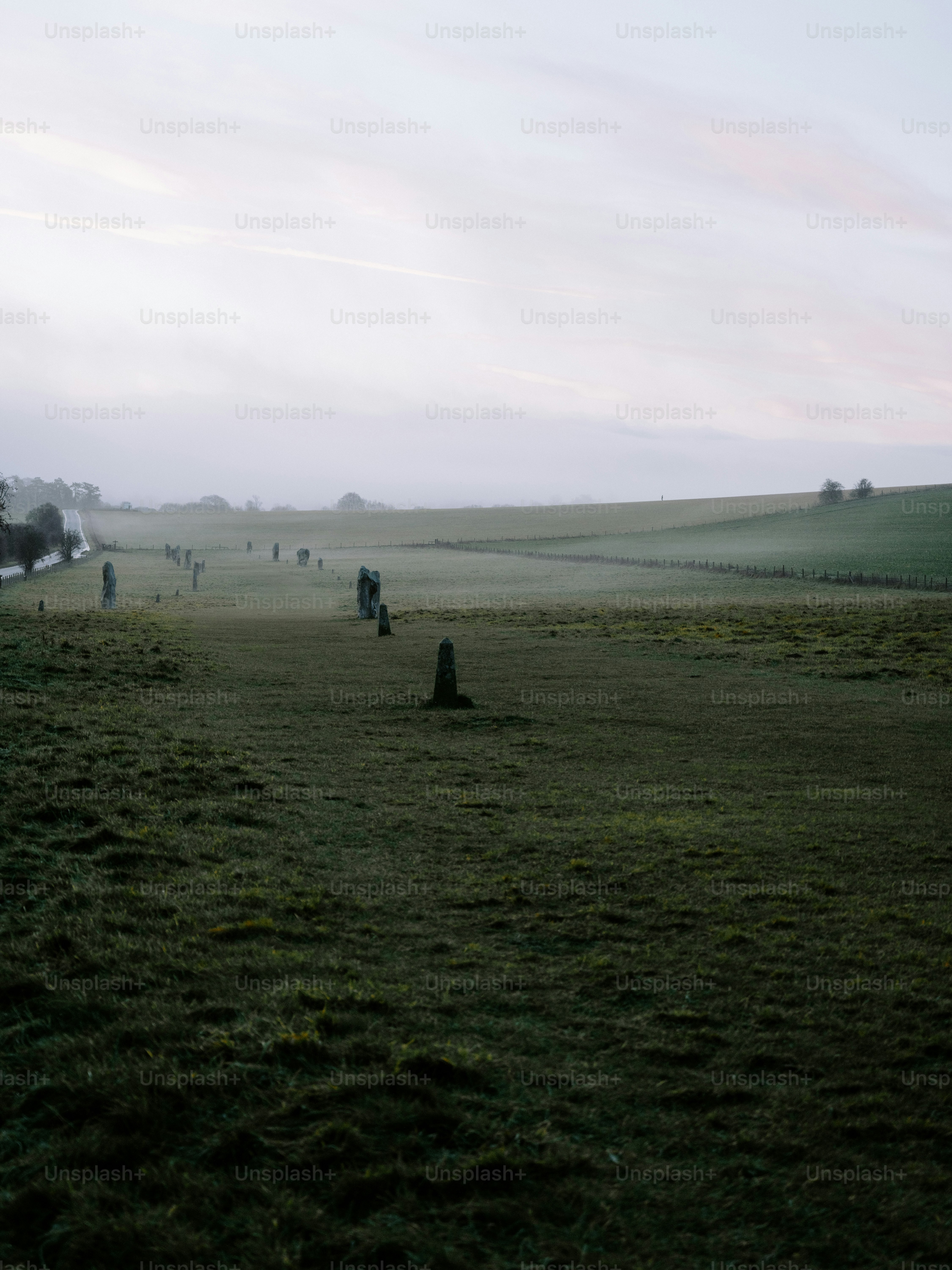 Misty morning over a green field with standing stones.