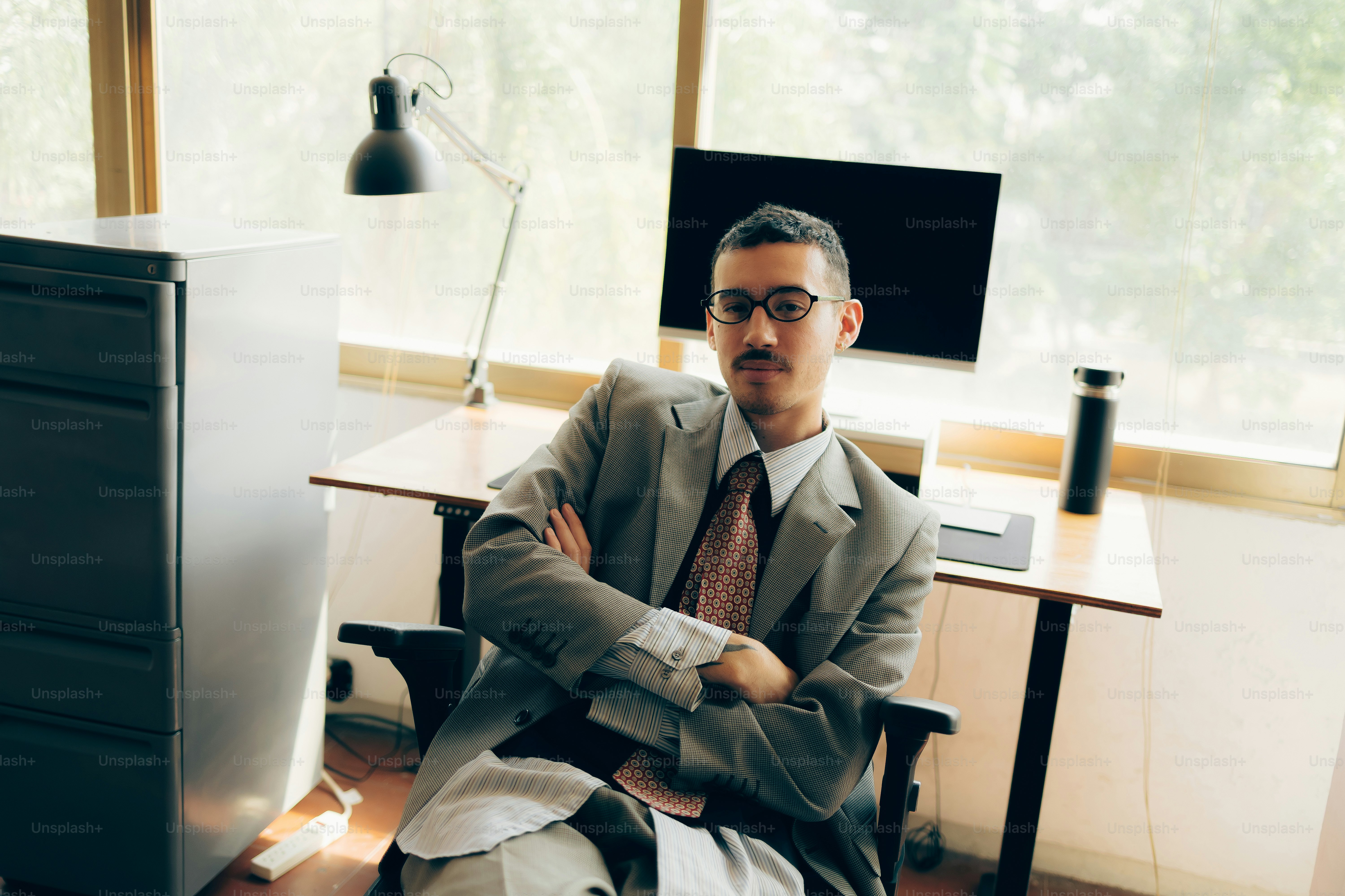 Man in suit sitting at office desk with arms crossed photo – Business ...