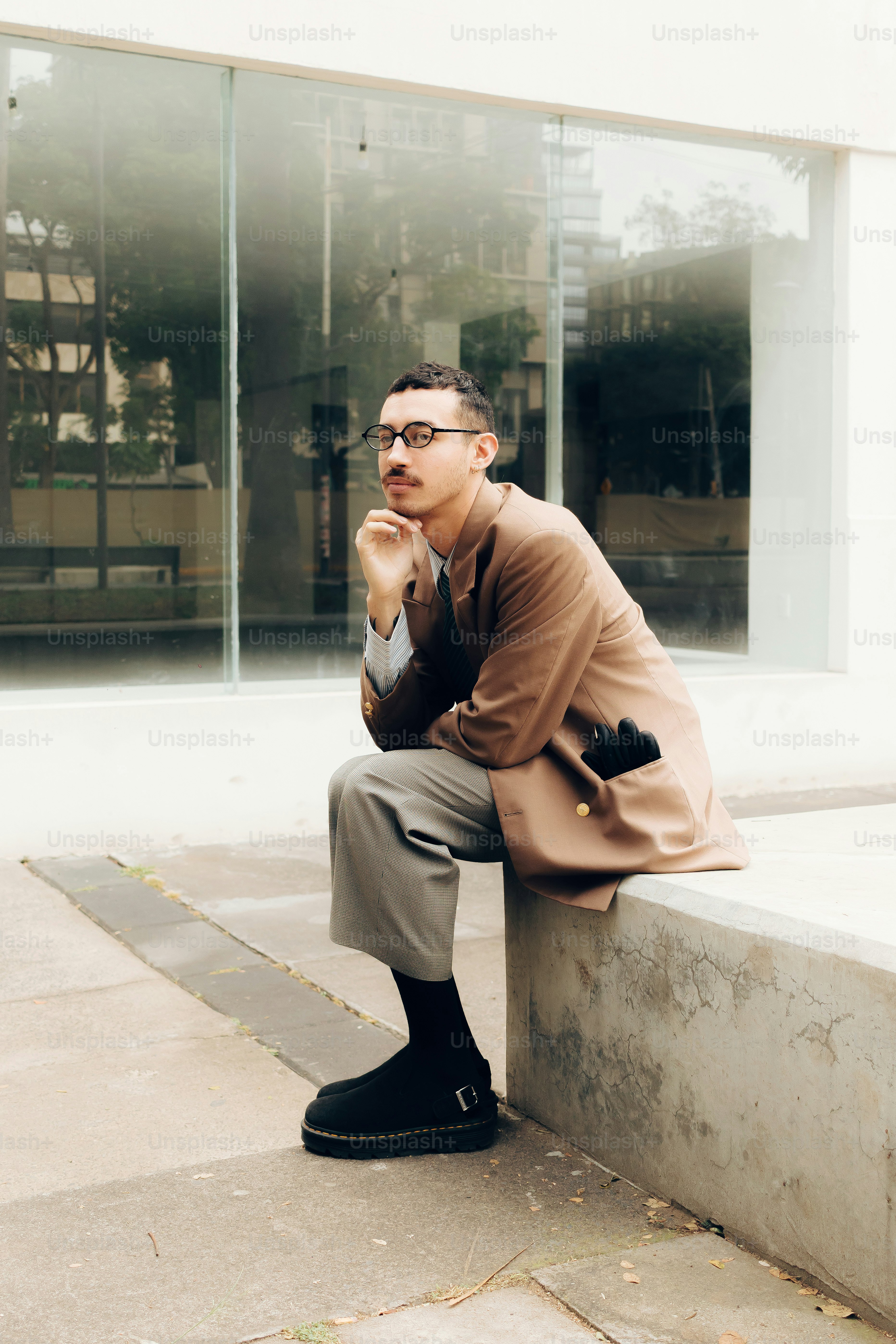 Hombre con un atuendo elegante sentado pensativo al aire libre. foto ...