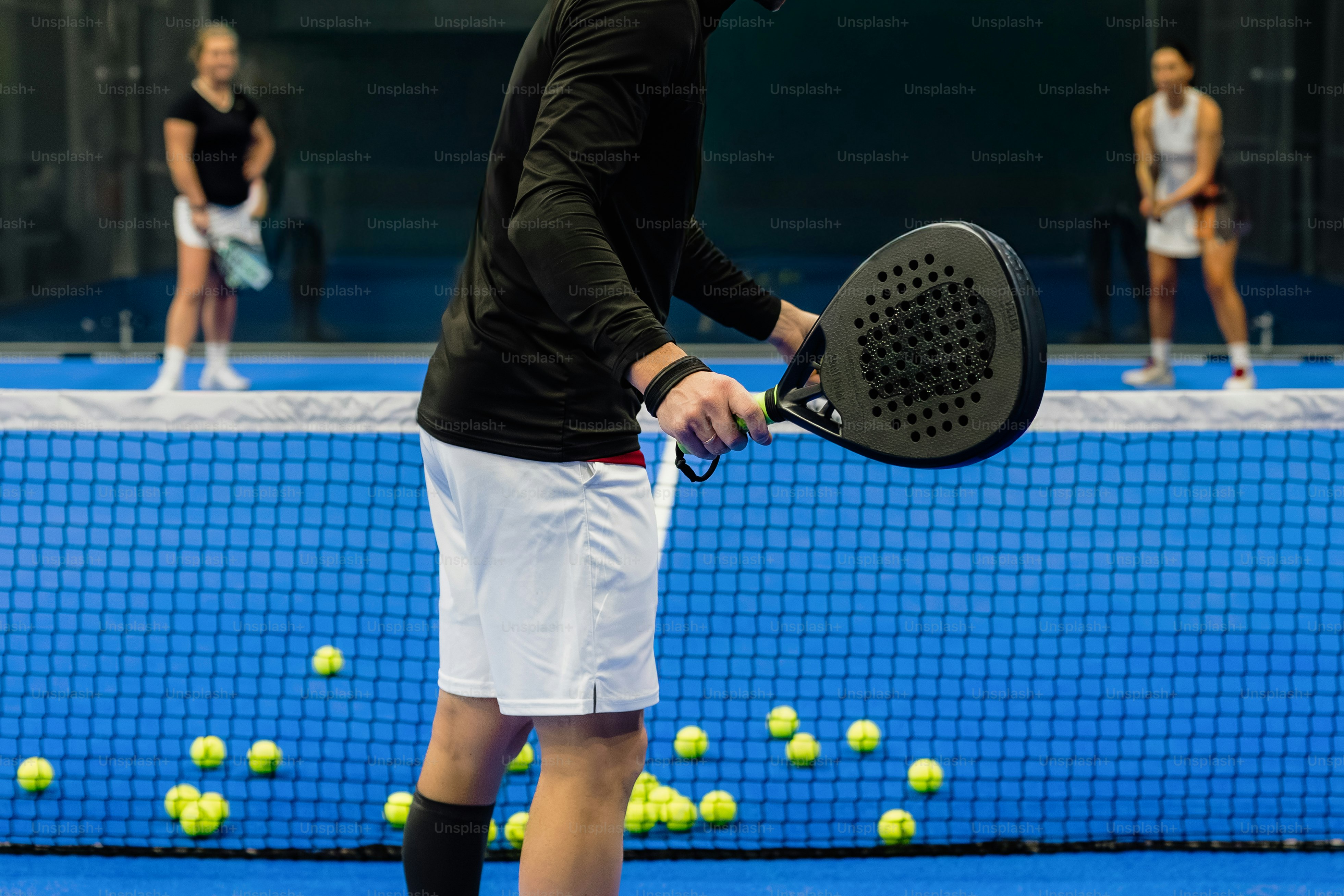 People playing padel tennis with balls on court