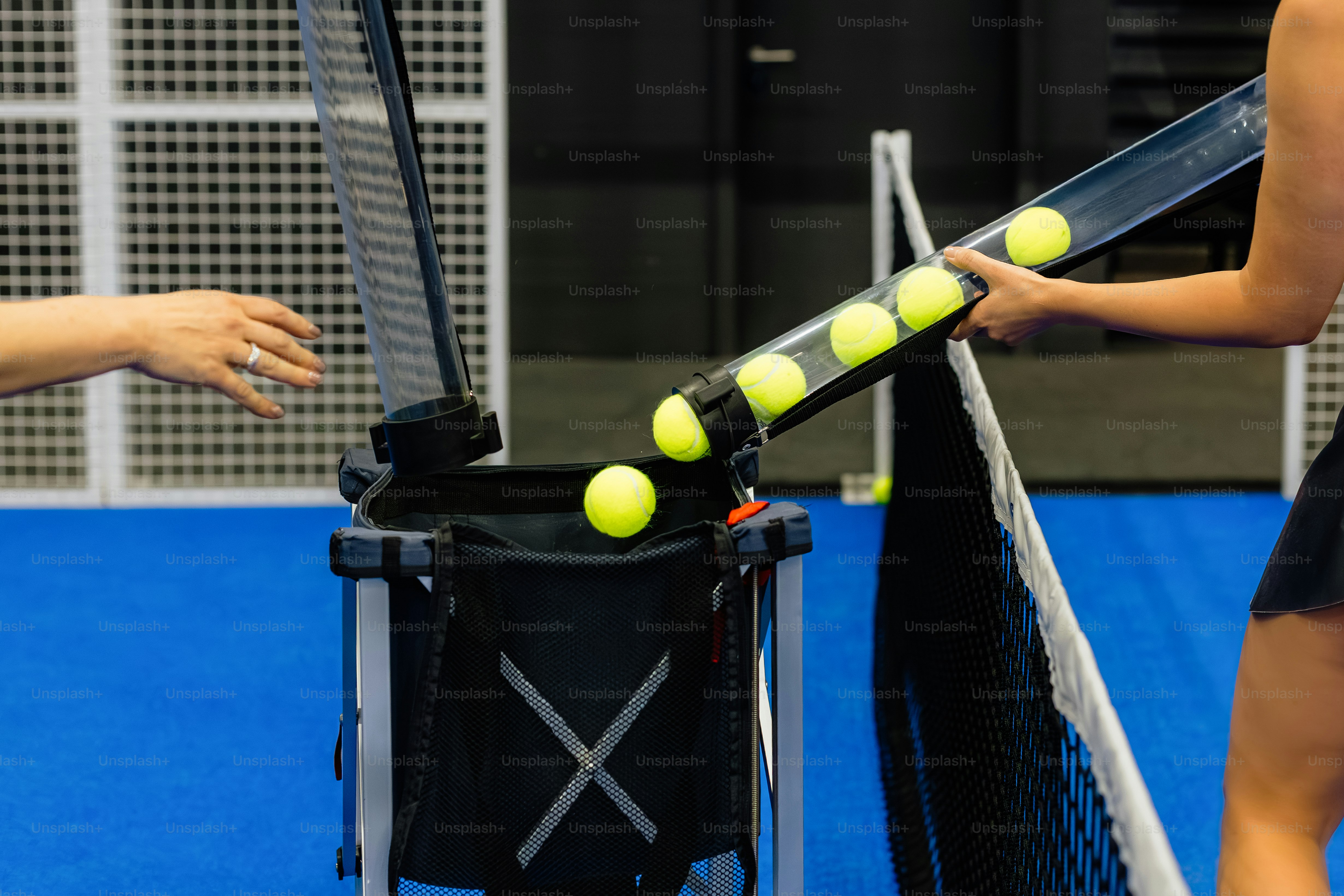 Tennis balls being loaded into a ball machine.