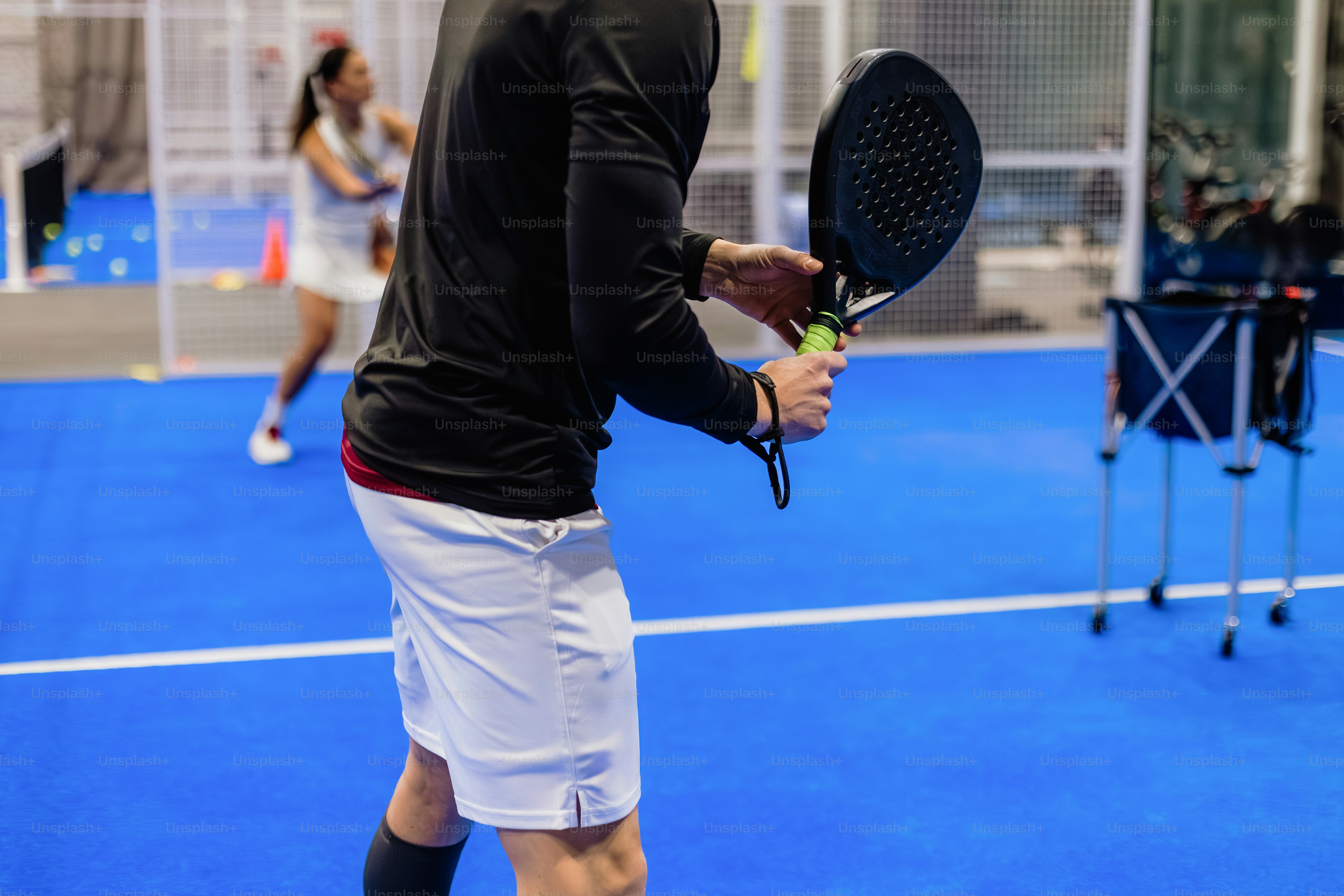 Two people playing padel tennis on a blue court.