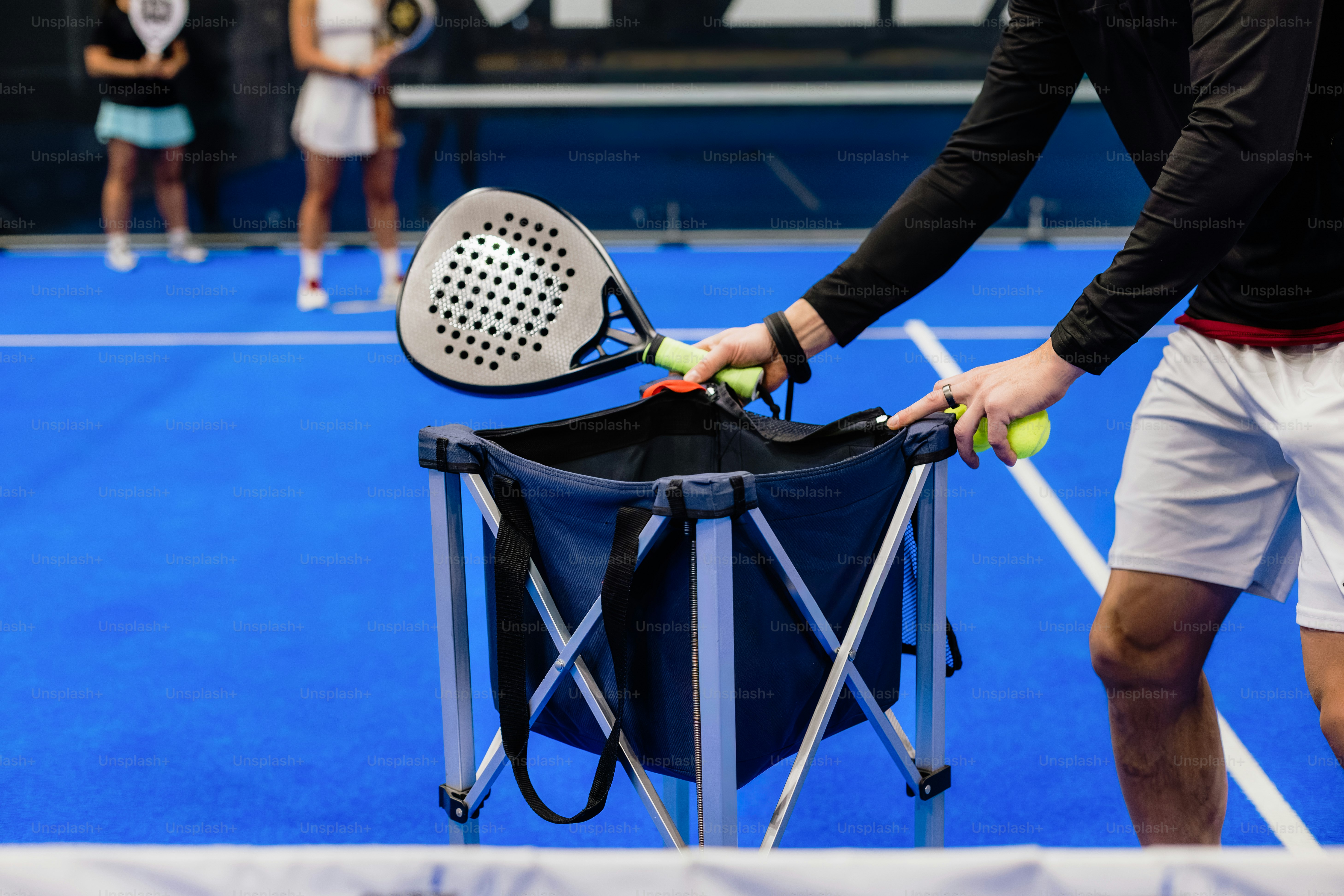Person placing padel racket into a basket