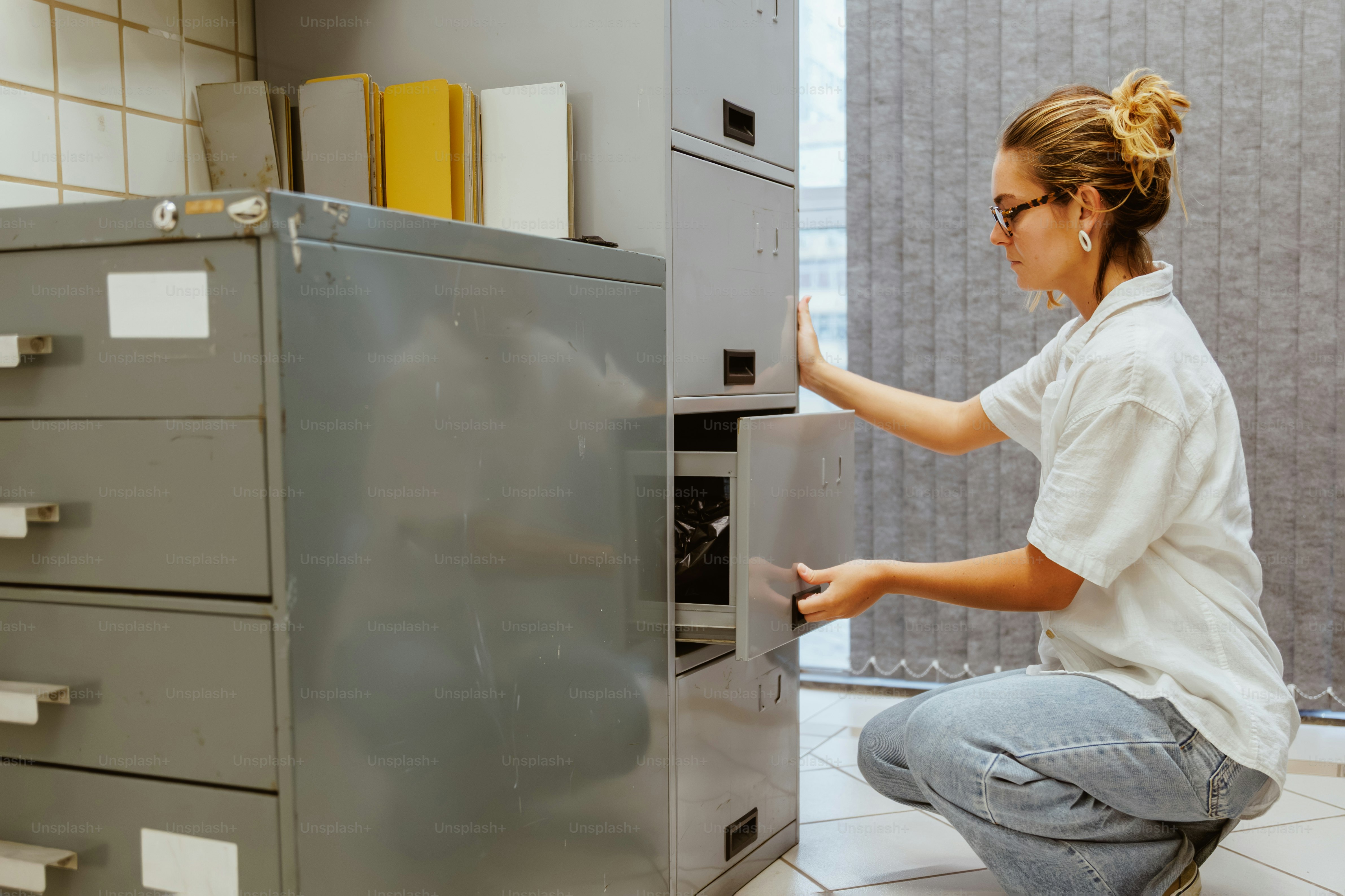 Woman opening a filing cabinet in an office. photo – Documents Image on ...