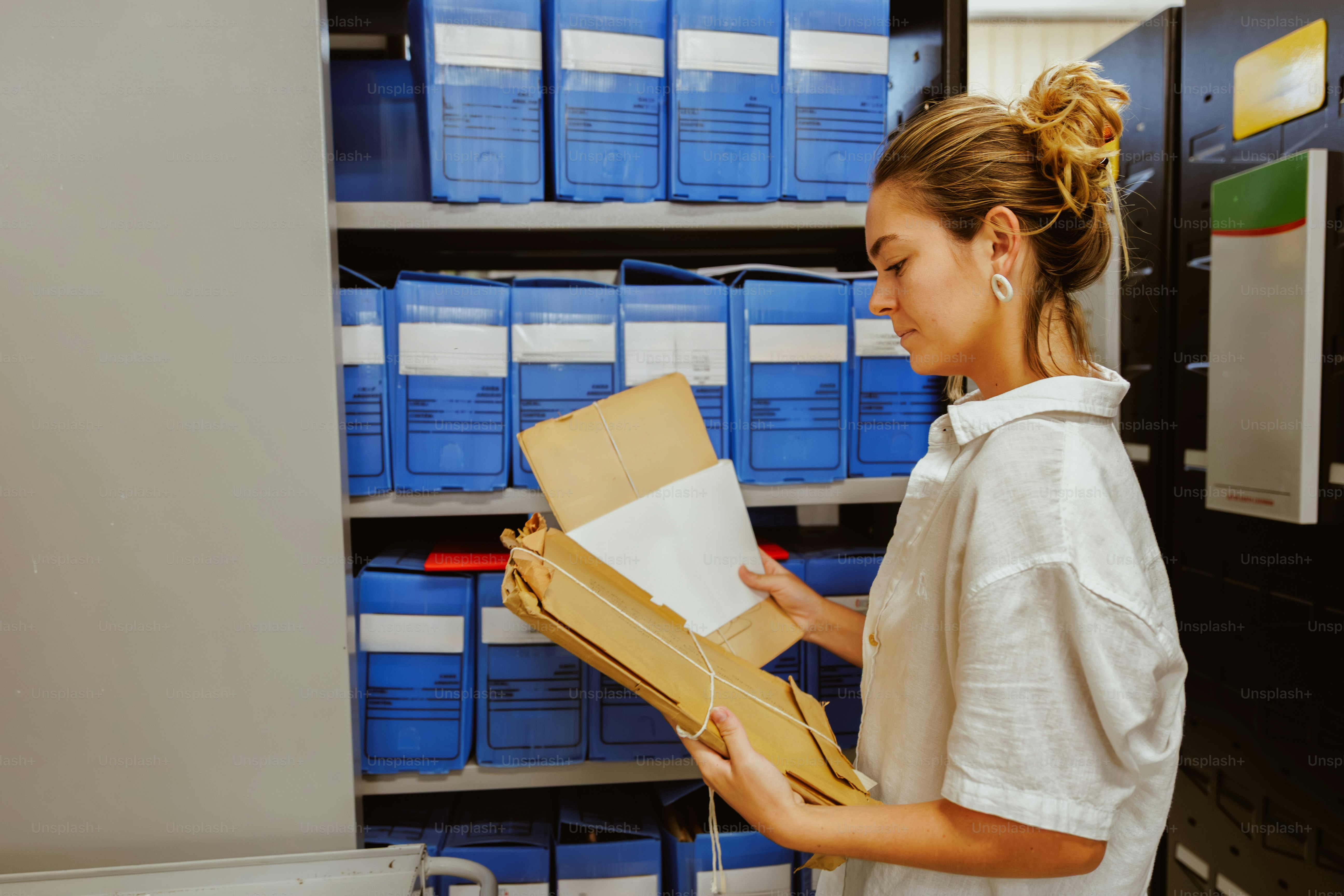 Young woman looking through files in a storage room photo – Portrait ...