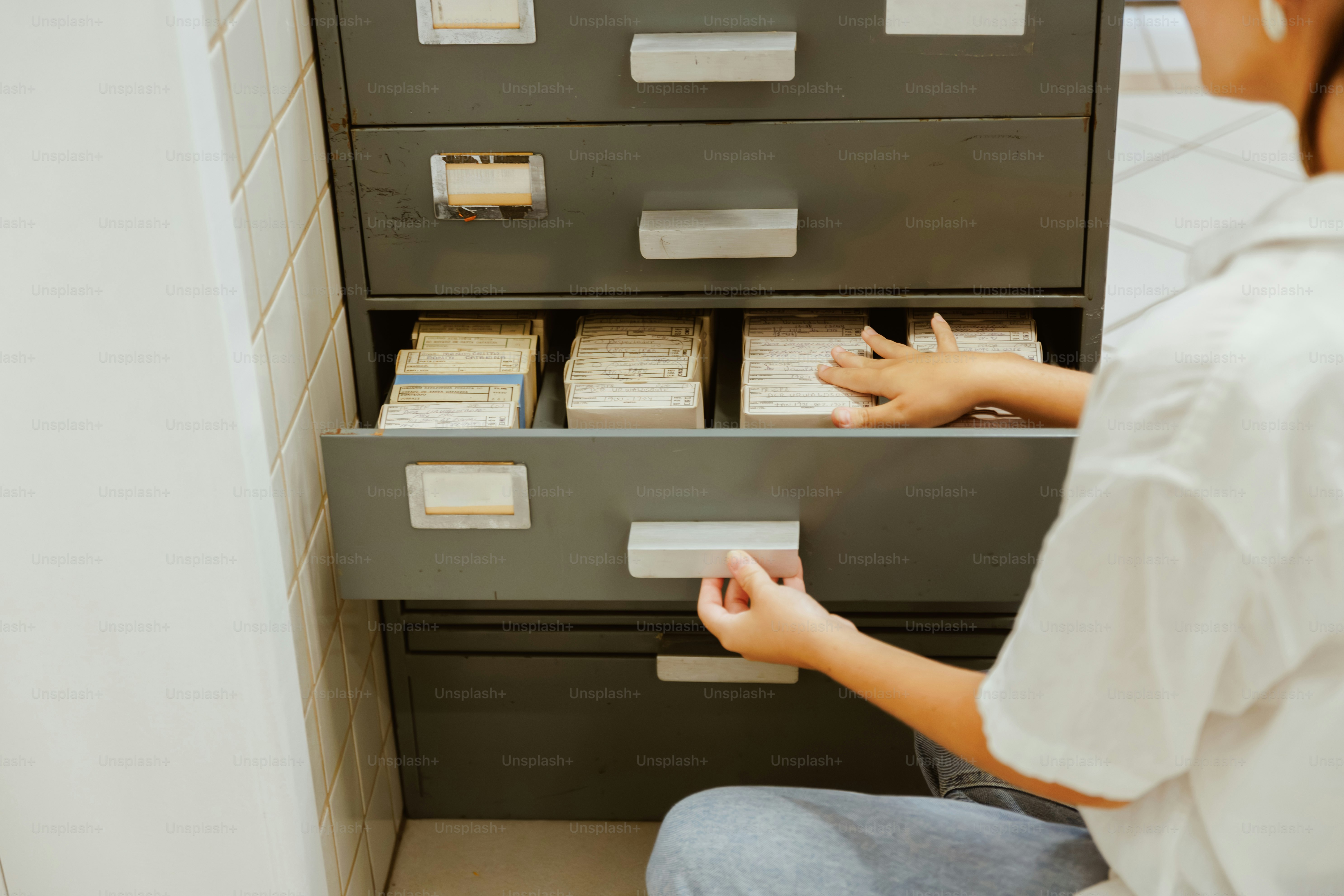 Person looking through stacks of paper in a filing cabinet.
