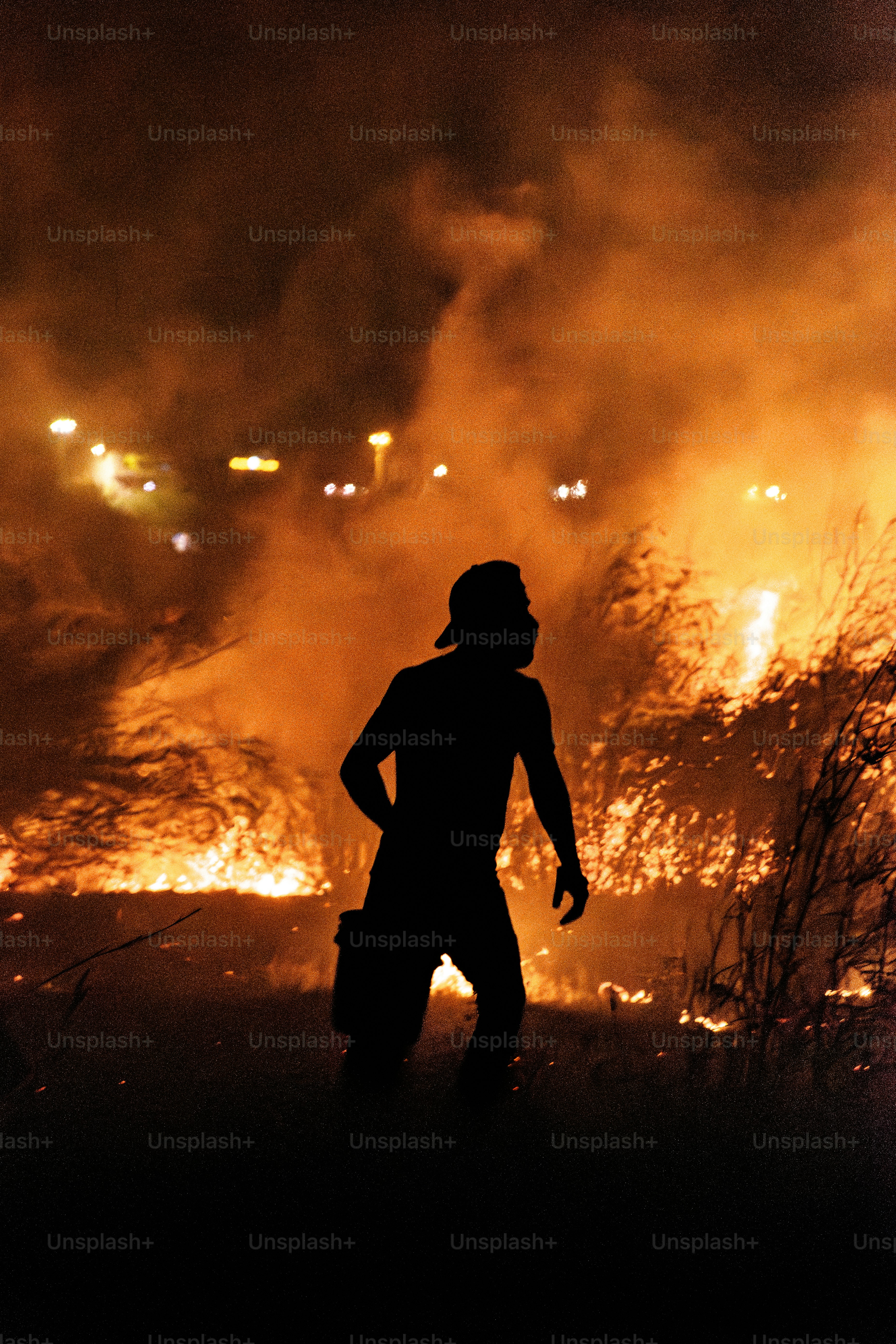 Silhouette of a person in a smoky, fiery landscape.