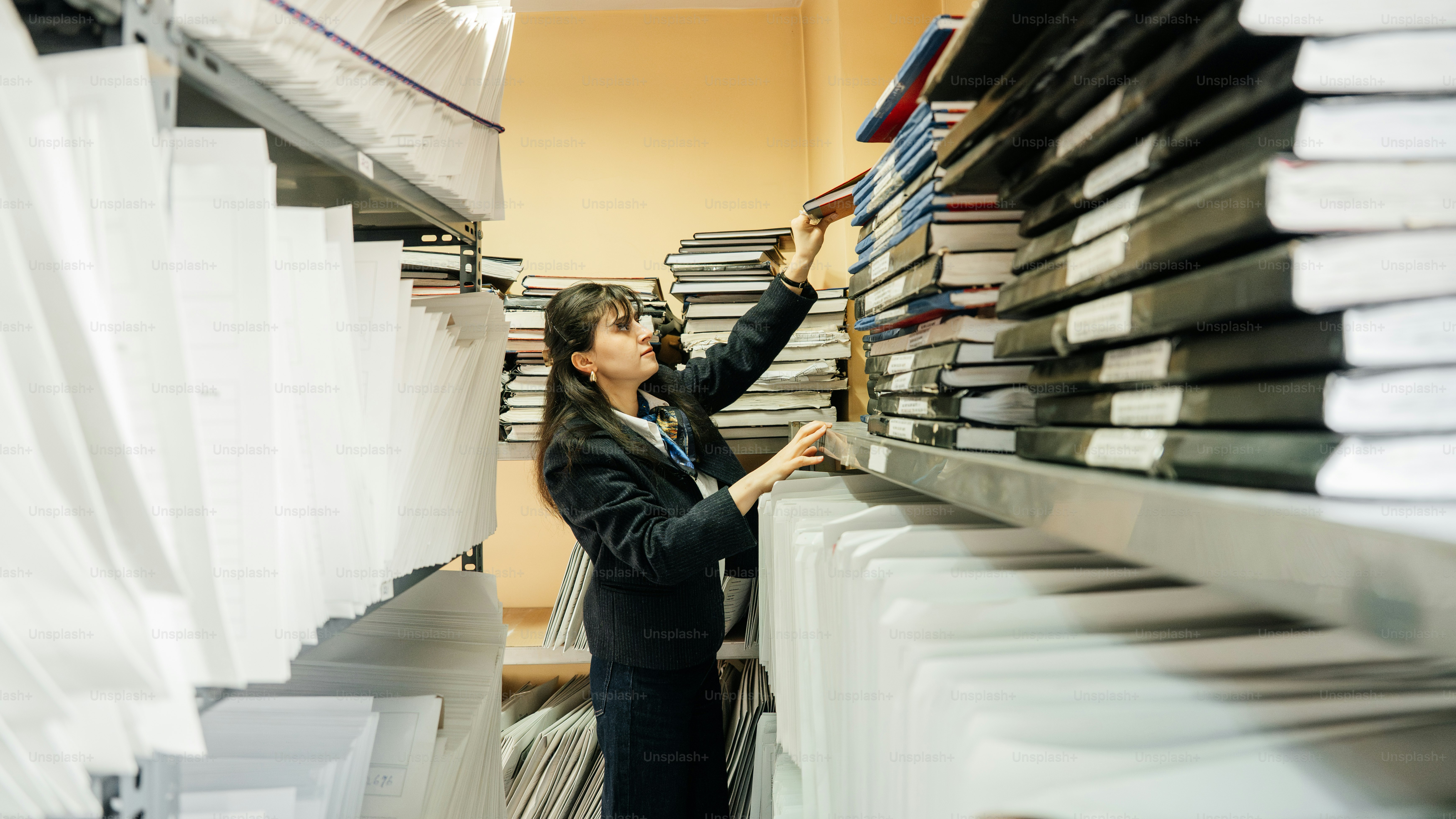 Woman in formal wear selecting book from shelf.
