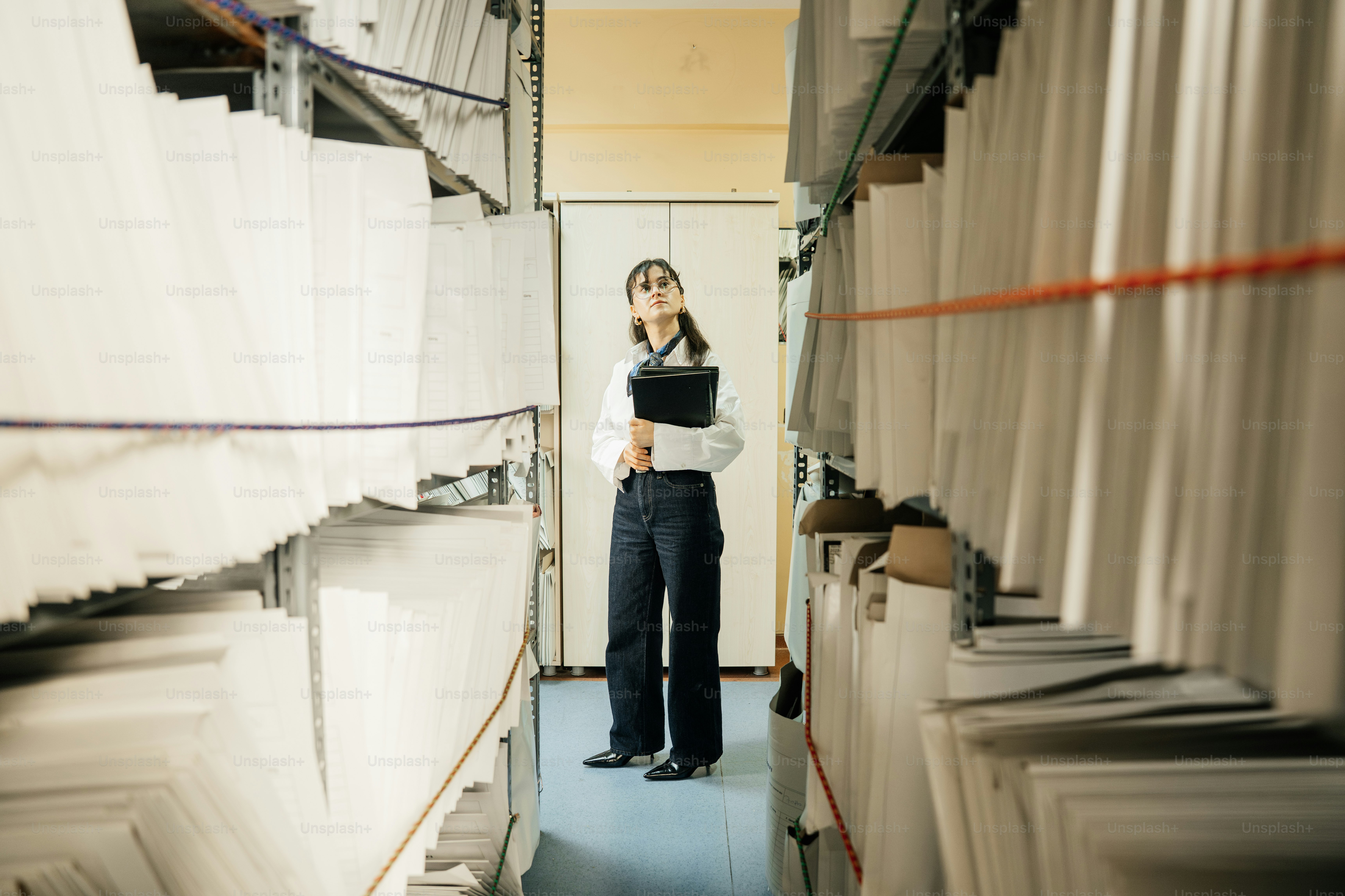 Mujer de pie entre filas de archivos en un archivo.