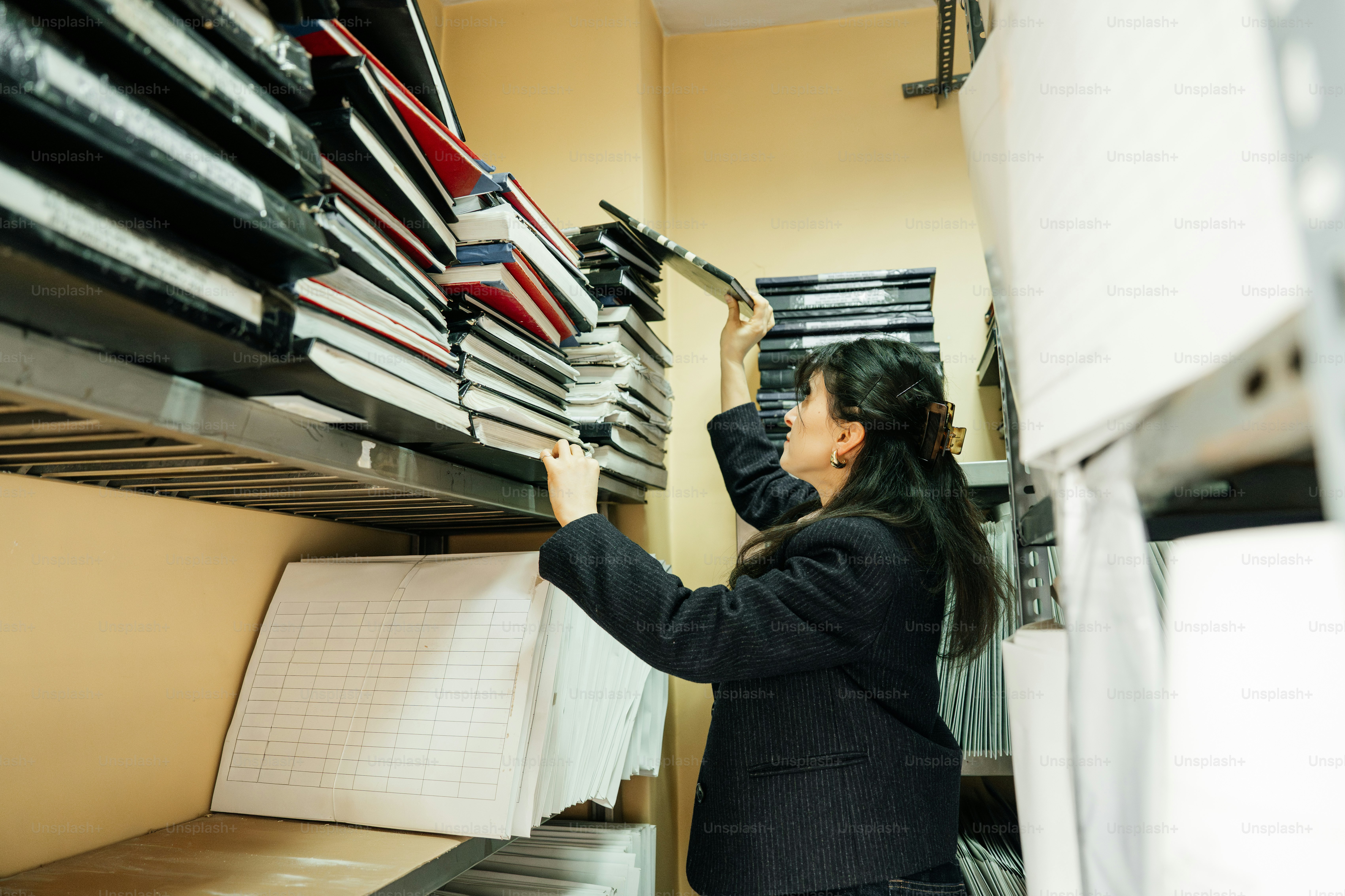 Woman reaching for books on a shelf in a library.