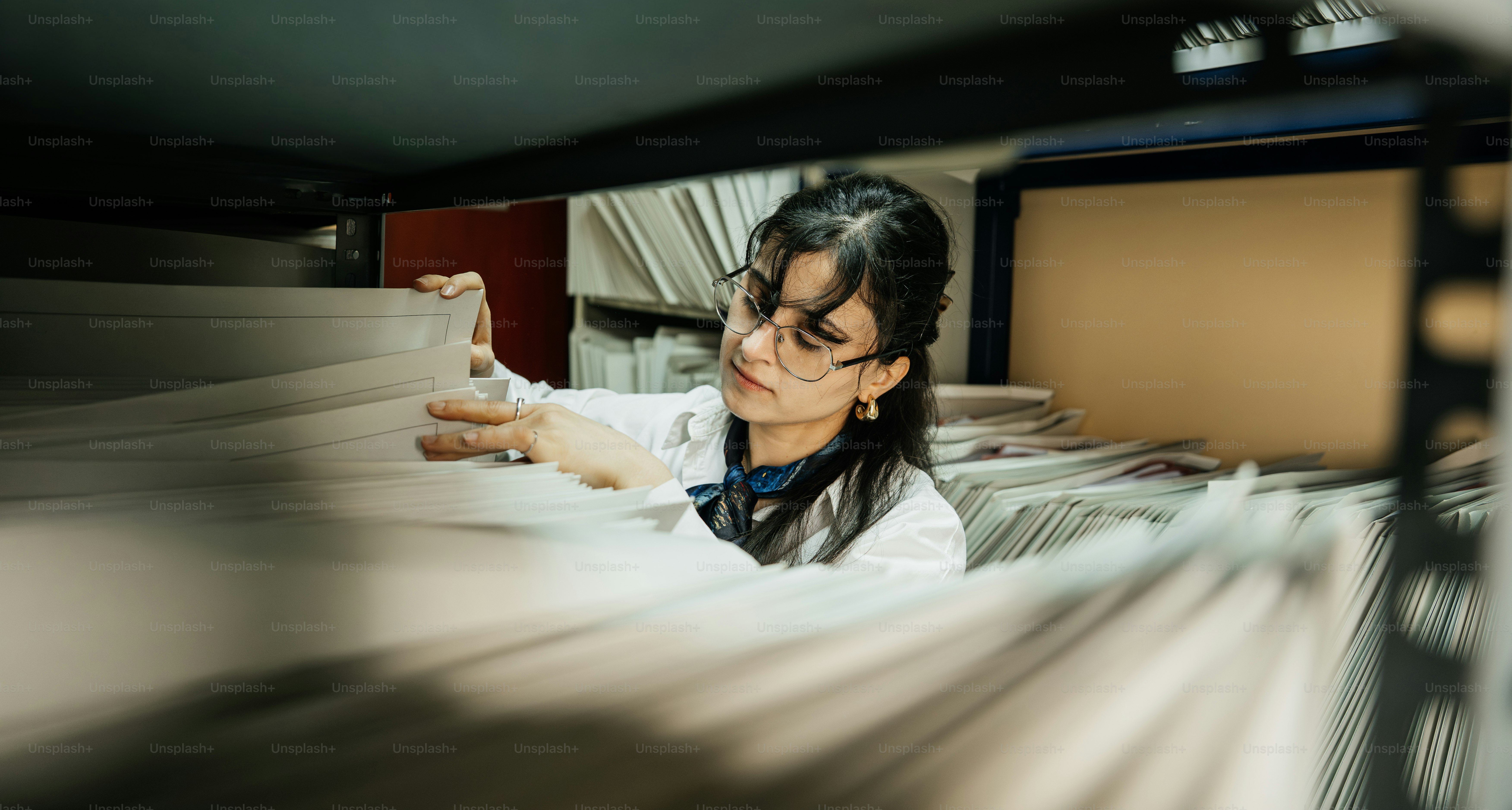 Wanita berjas lab melihat file di arsip