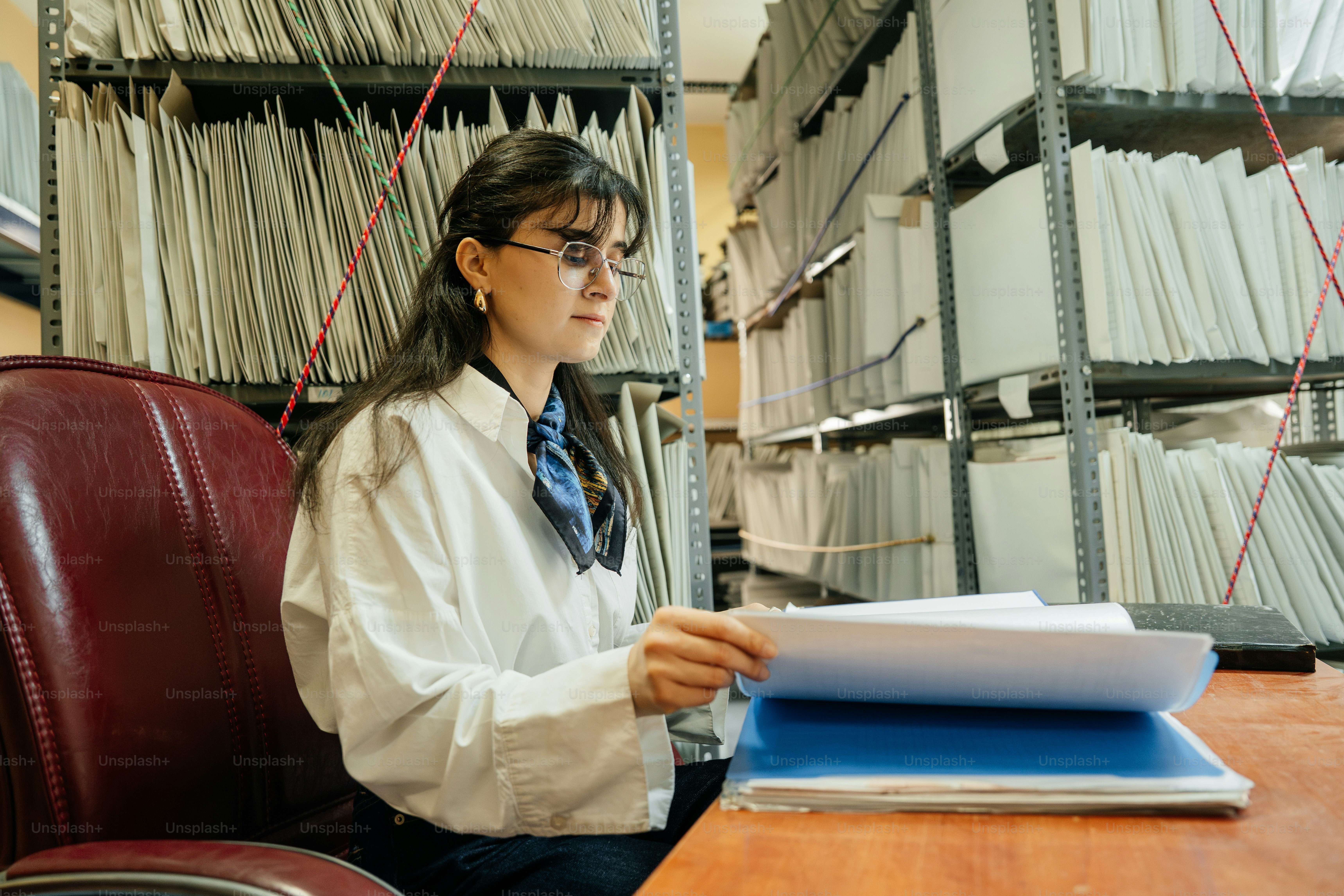 Woman reviewing documents in a file-filled office.