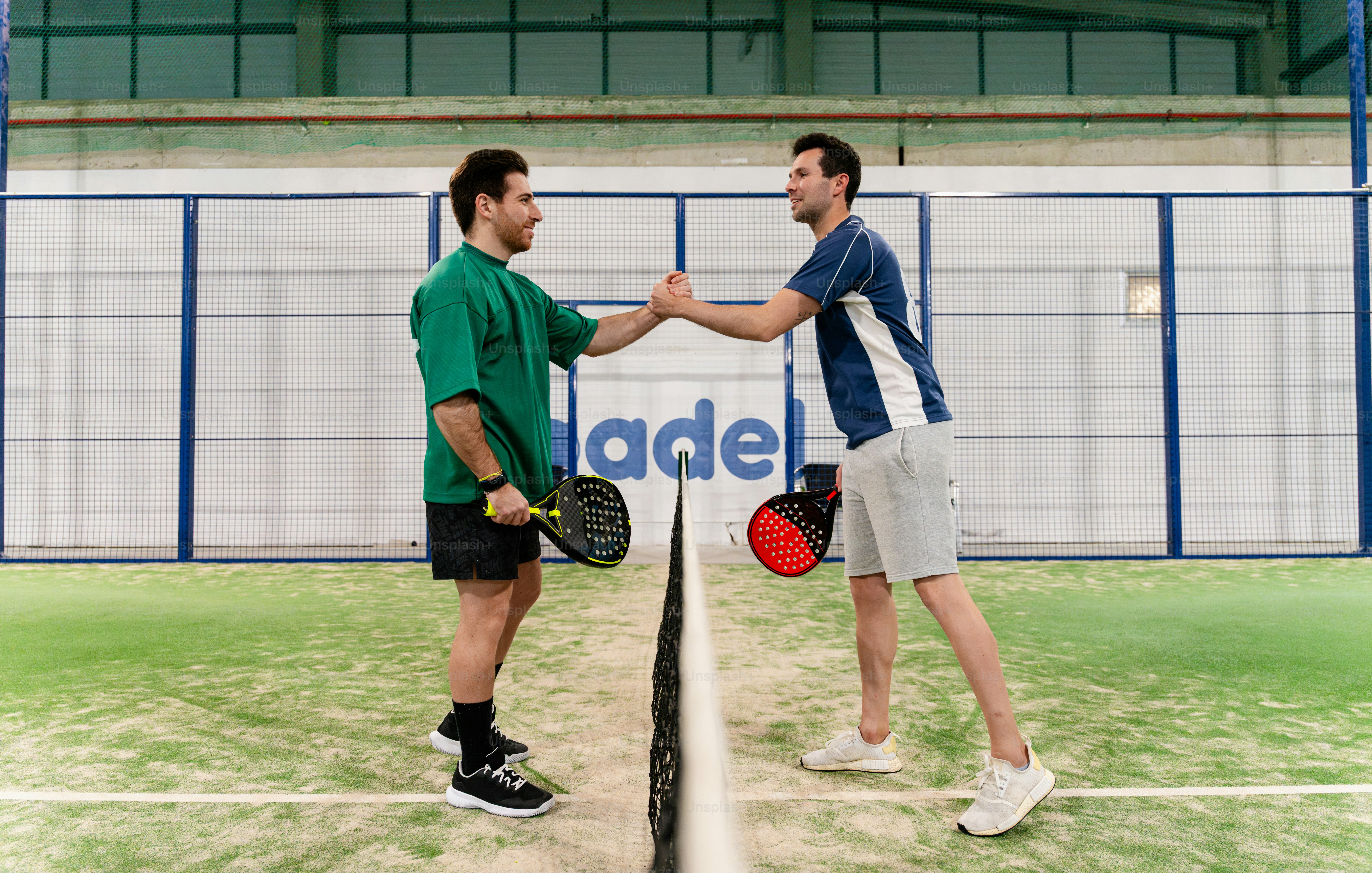 Deux hommes se serrant la main au-dessus d’un filet de tennis
