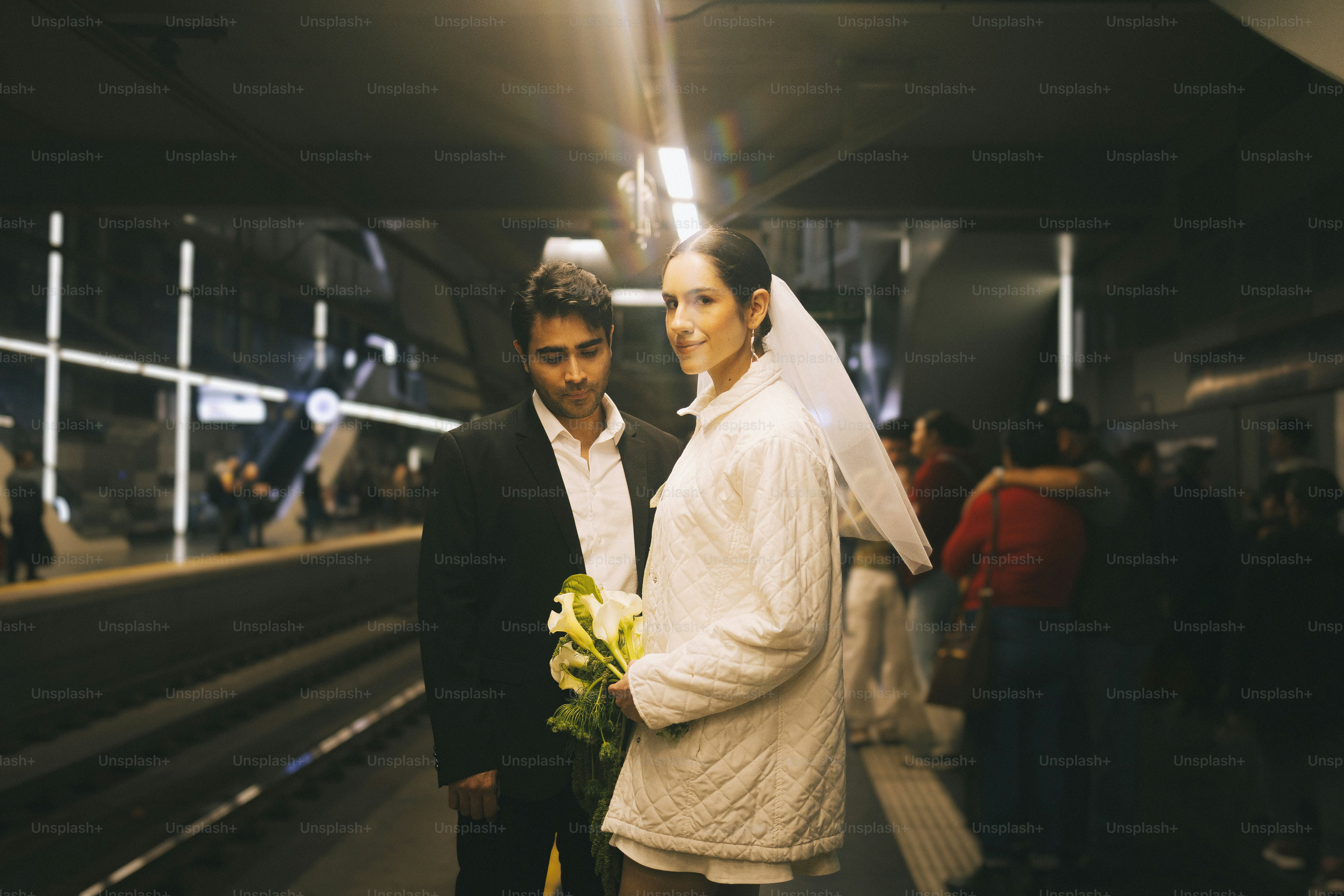 Bride and groom stand on subway platform