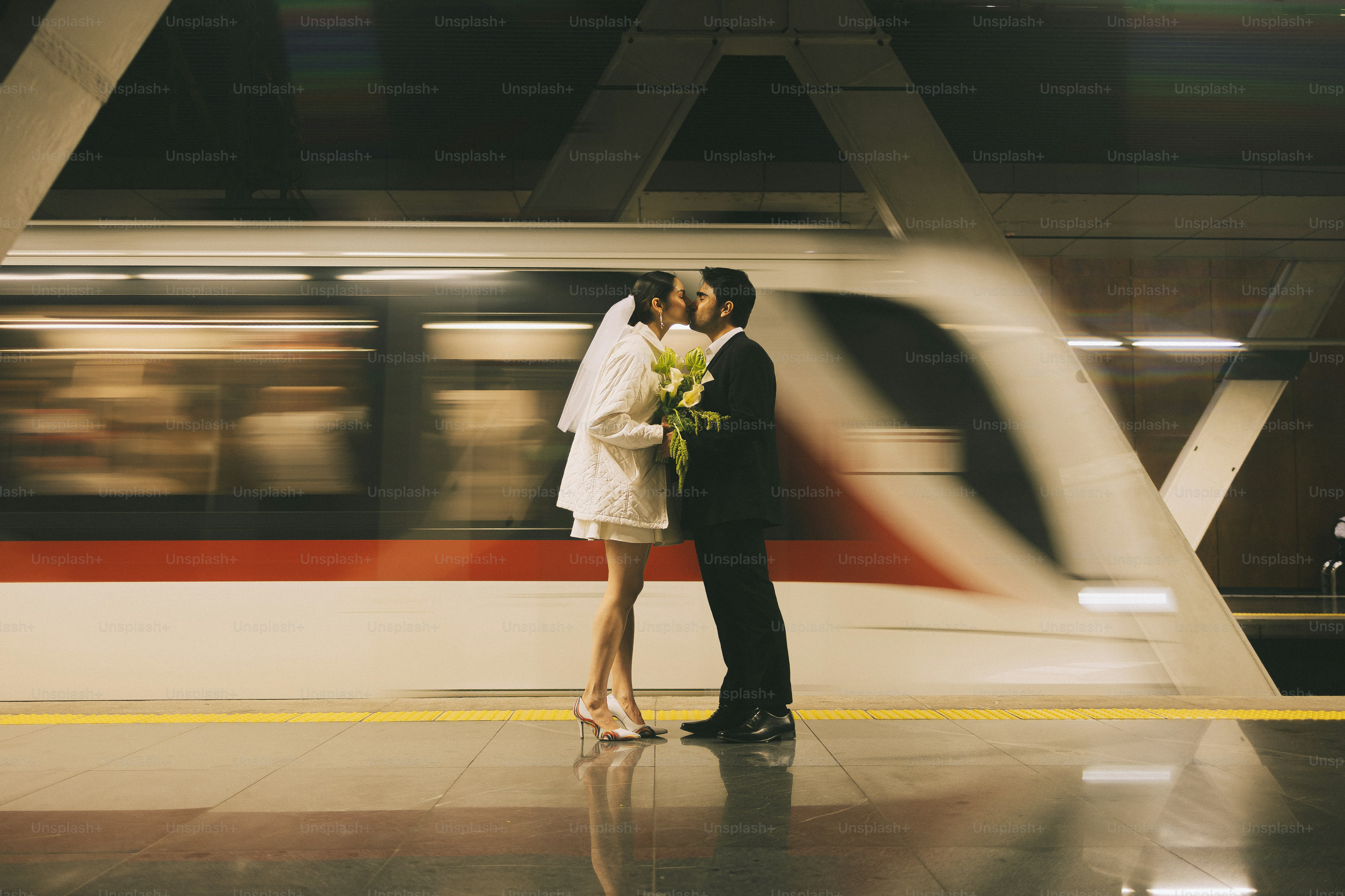 Bride and groom kissing on a train platform