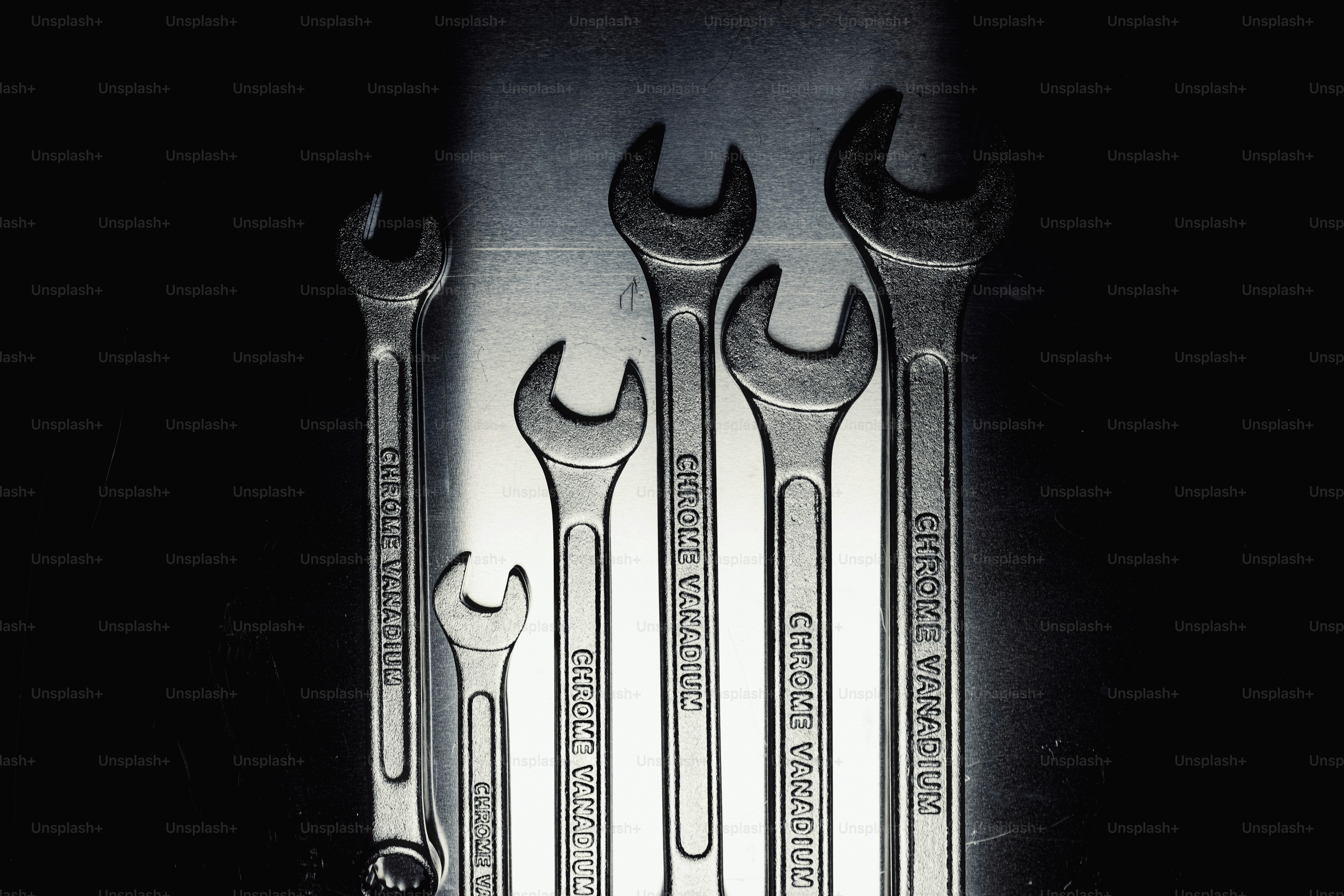 Five wrenches of varying sizes on a dark background