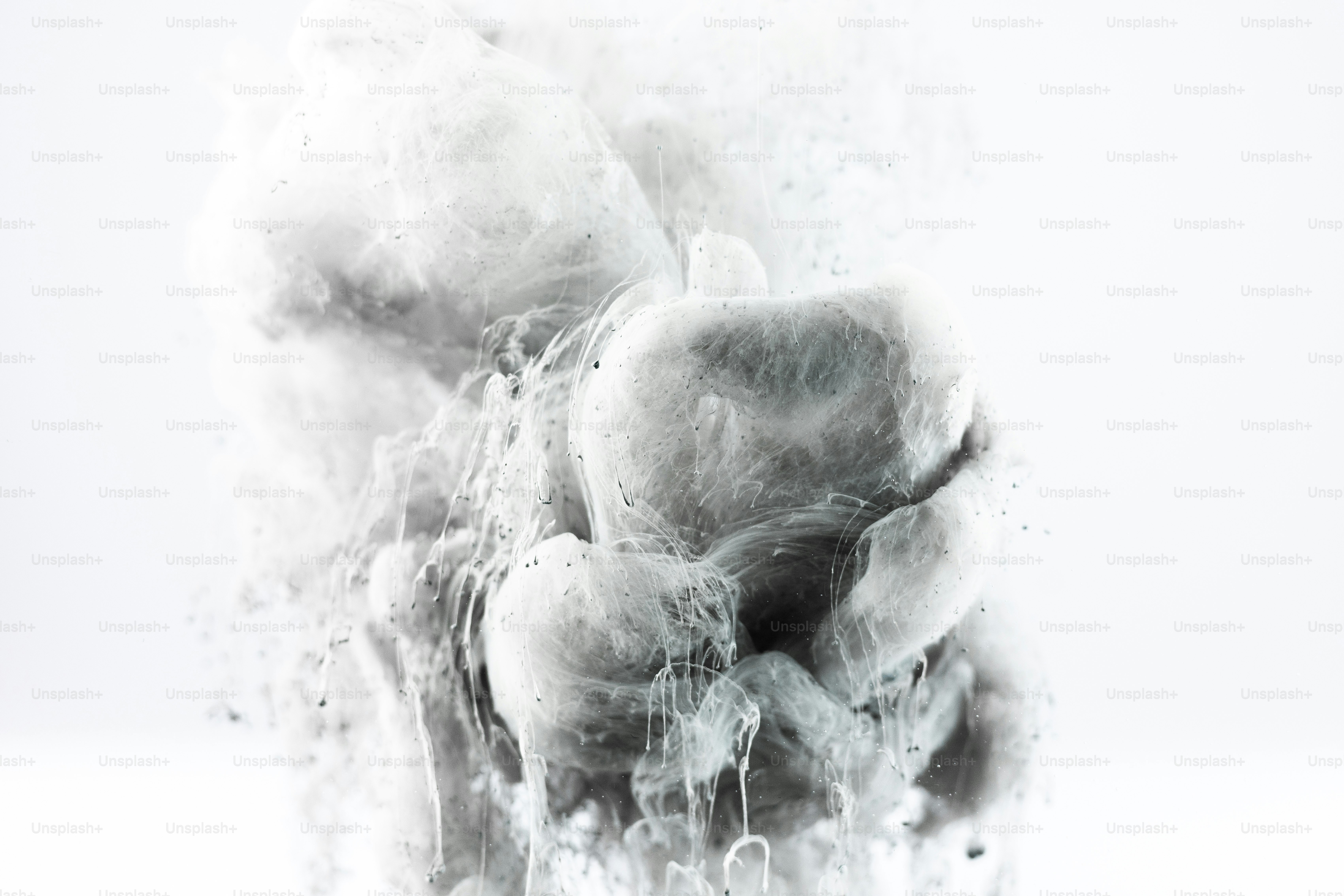 White ink swirling in water creating abstract shapes