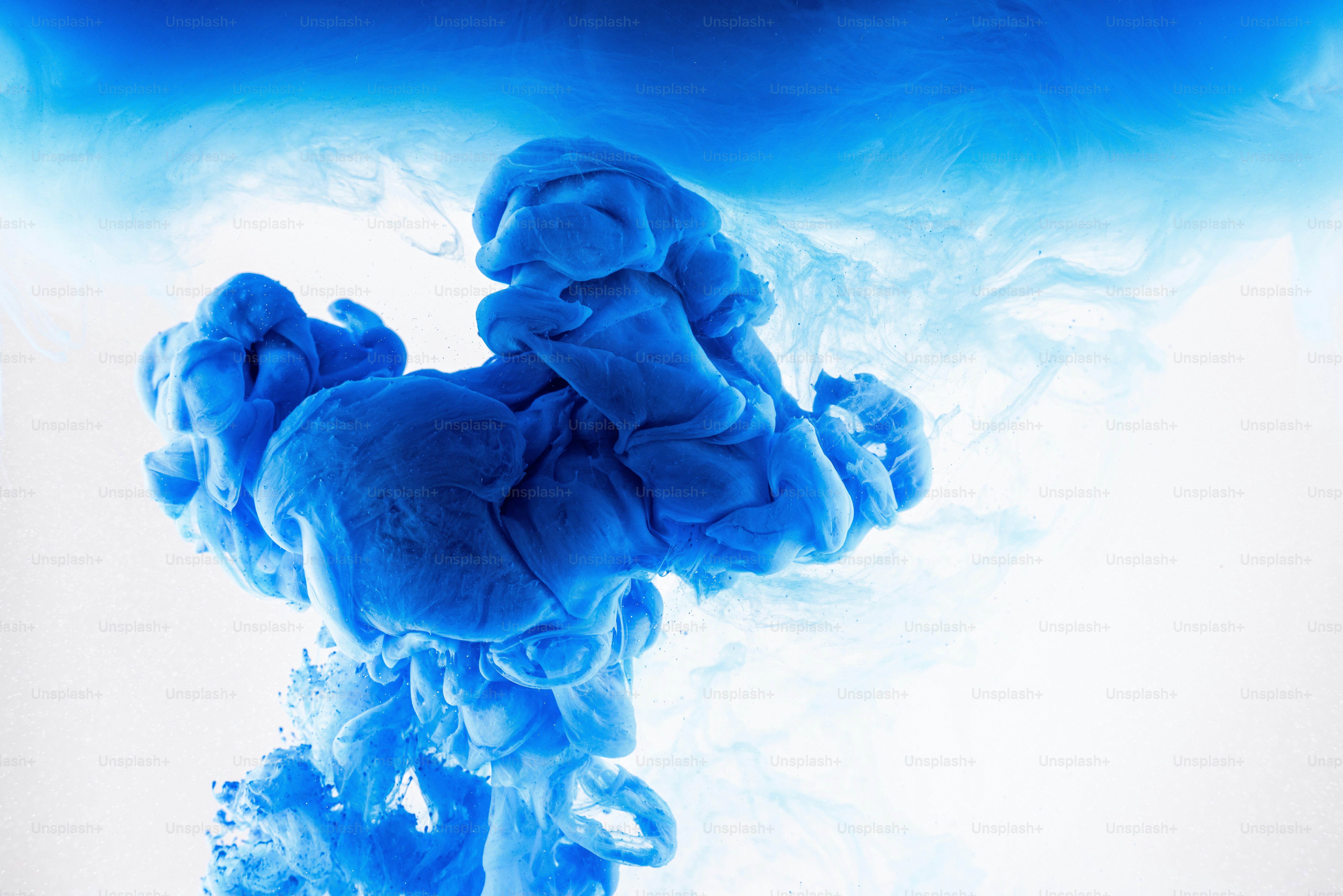 Blue ink cloud swirling in water against white background.