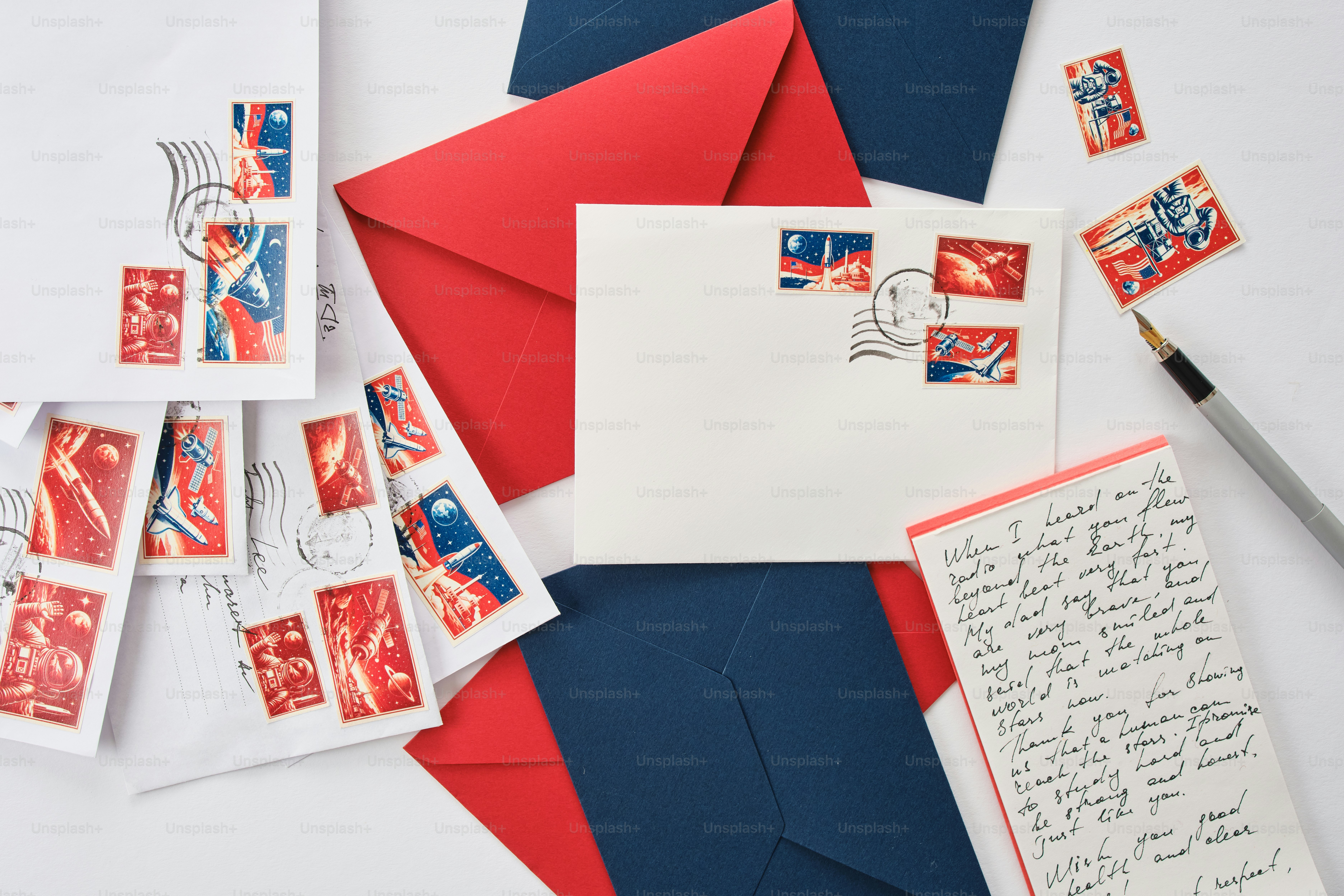 Buste, francobolli e una penna su una superficie bianca.