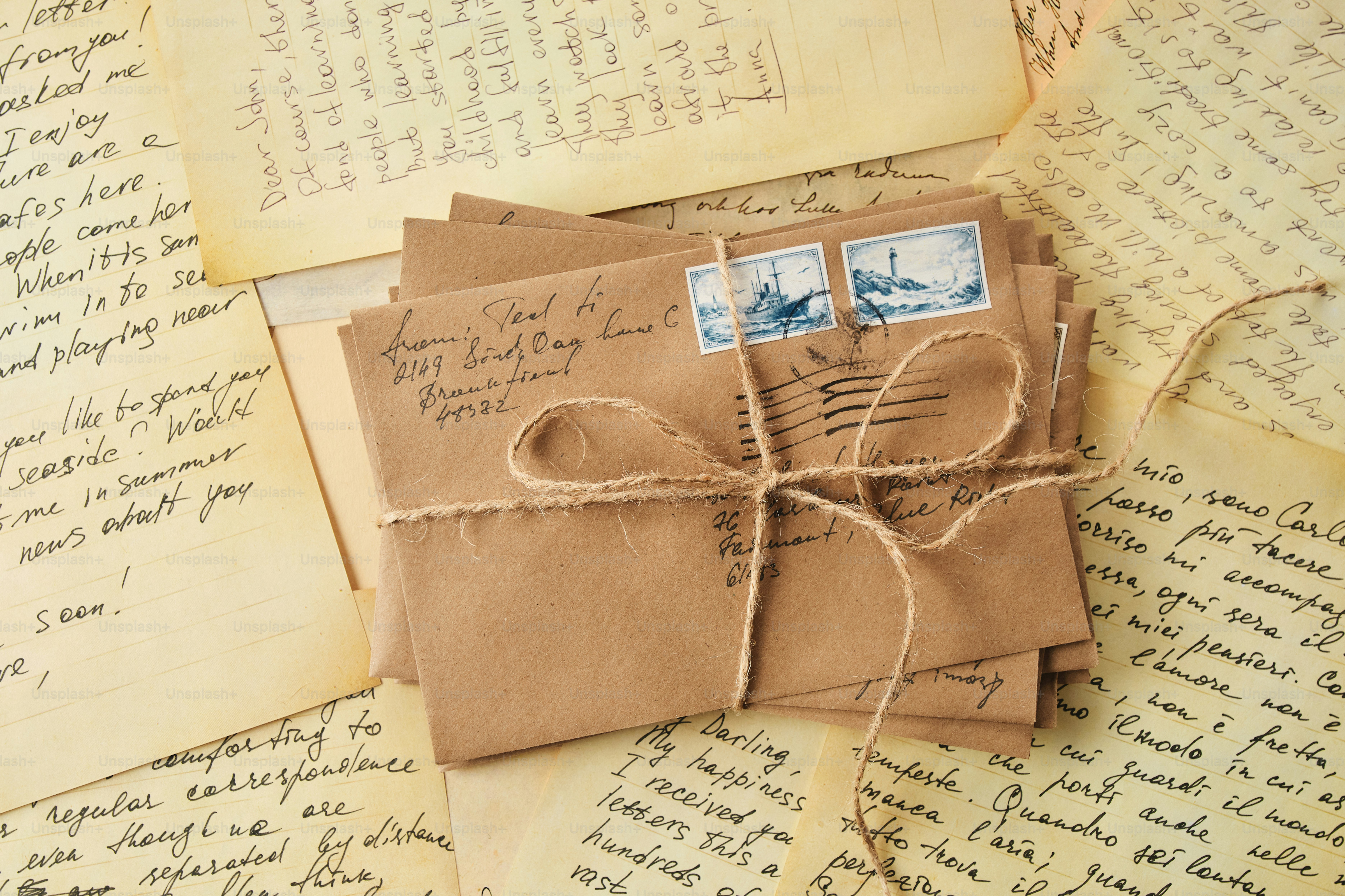 Pila di buste marroni legate con spago, circondate da lettere.